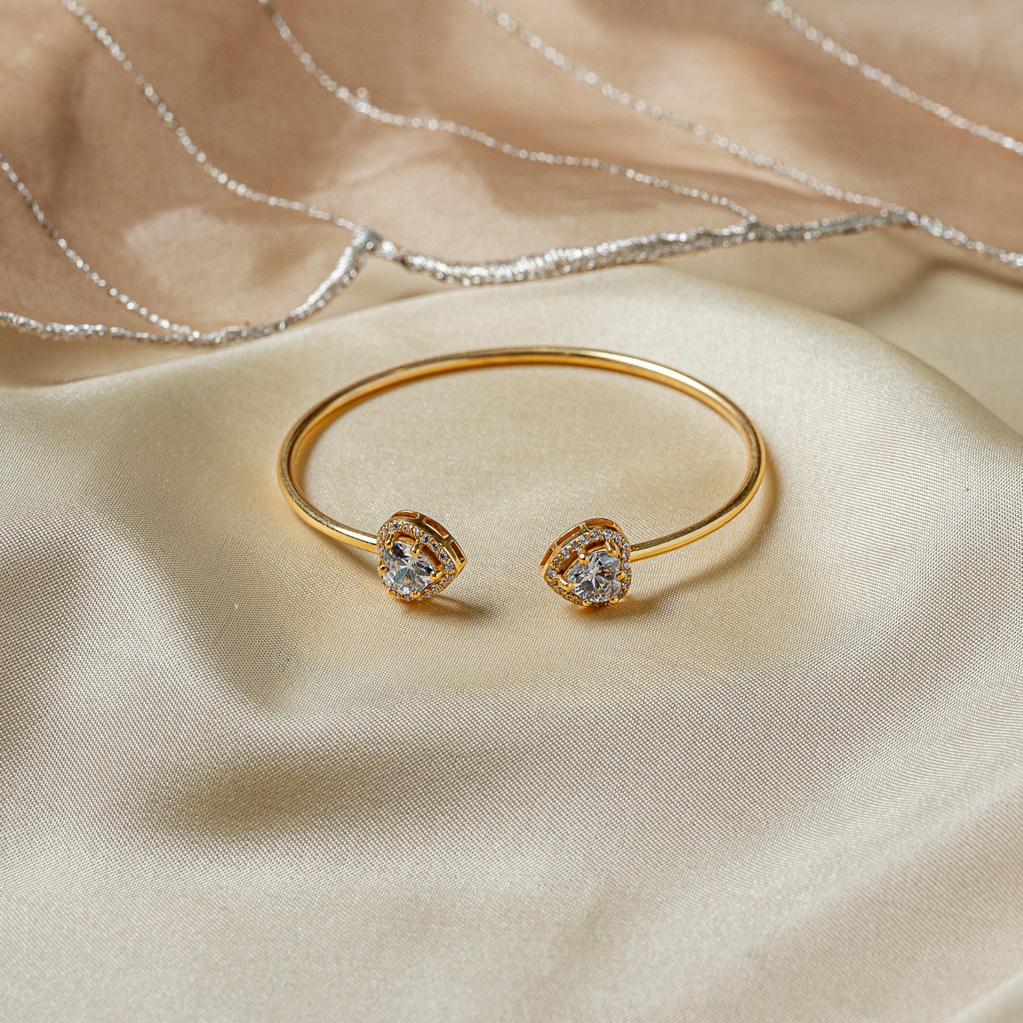 Open cuff on slim round wire with twin heart cut CZ terminals in gold plated 925 silver