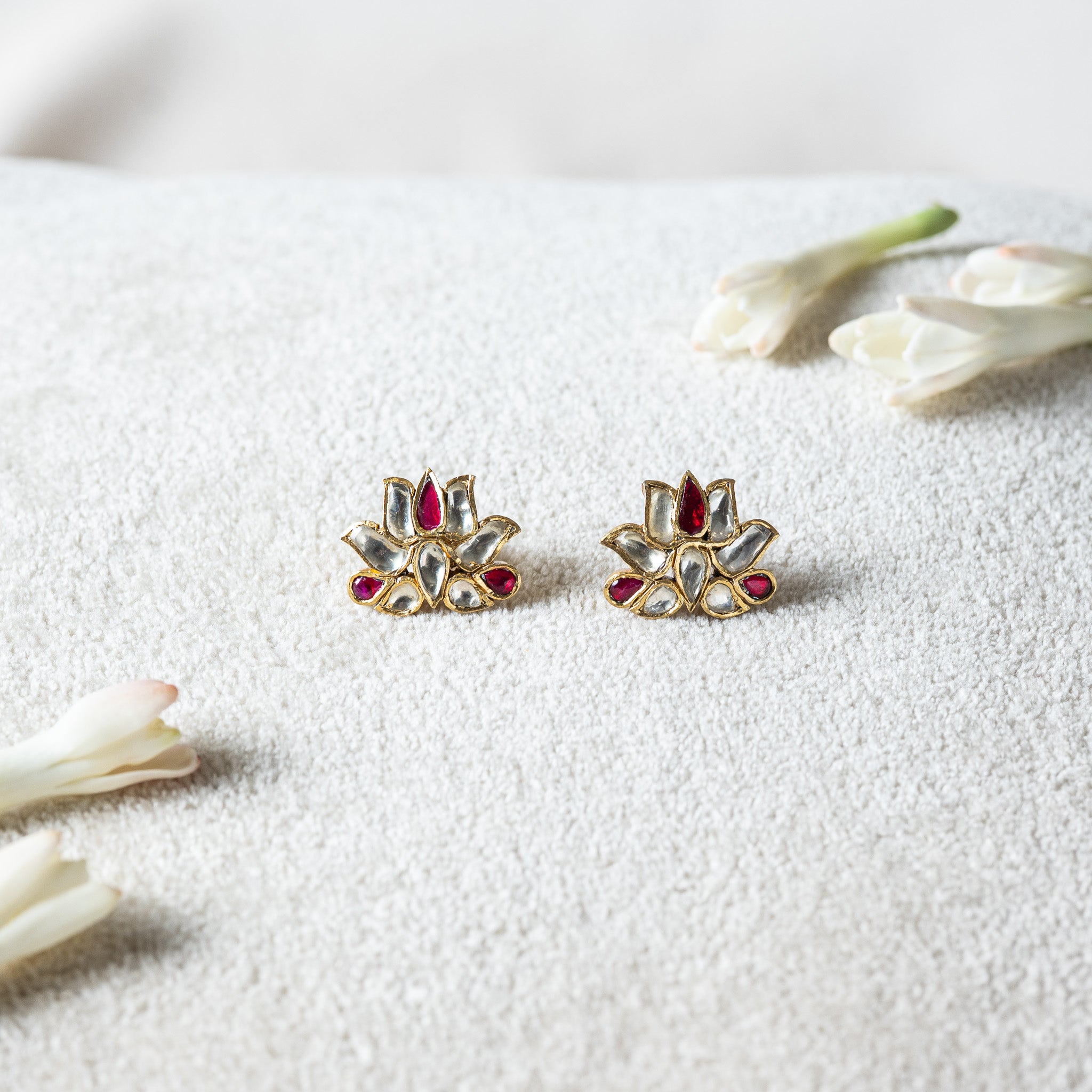 Kundan lotus studs with three red petal stones among flat cut white kundan in antique gold