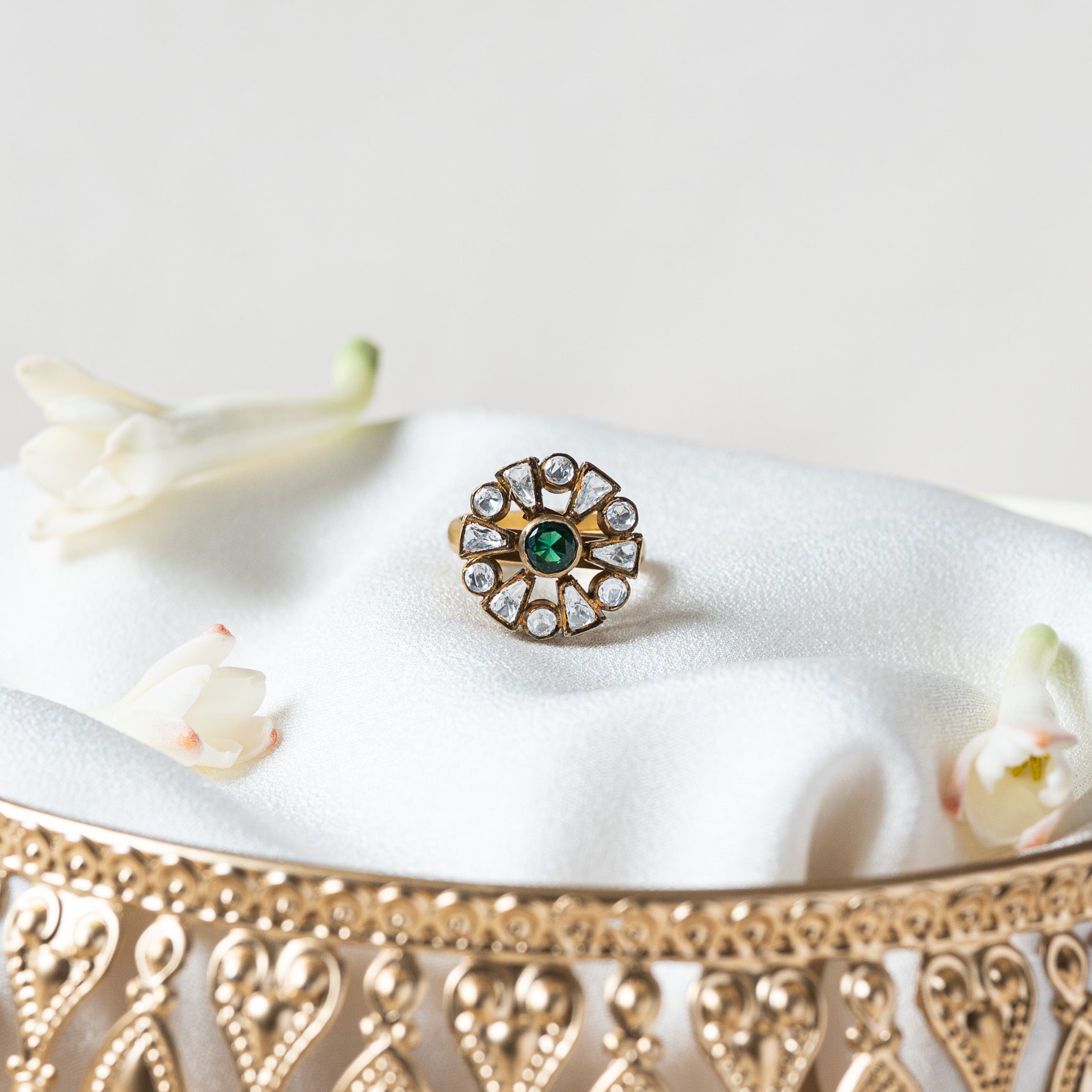 Victorian rosette ring with a round green stone ringed by twelve uncut white stones in dark rims