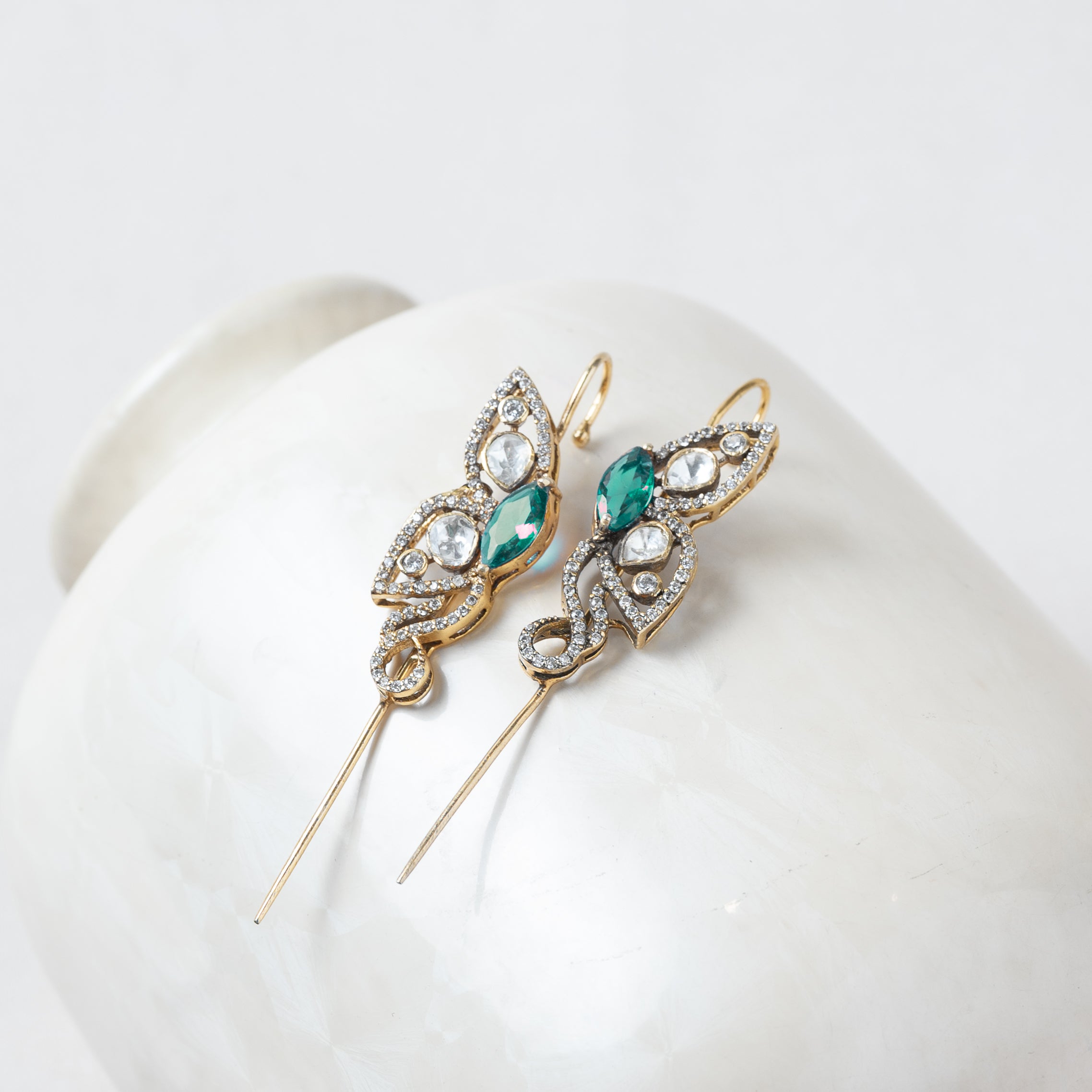 Side view of the green ear cuff showing the gold wire that curves over the top of the ear