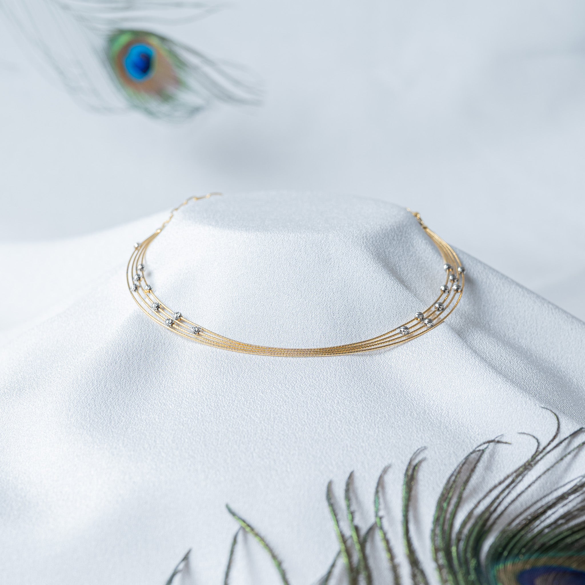 Front view of the four fine chains held apart with faceted balls staggered across them