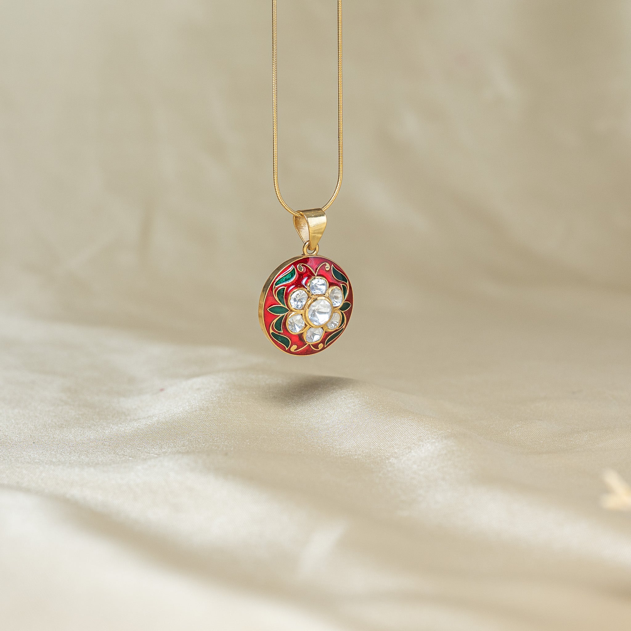 Close crop of the red fired enamel, the seven kundan petals and the green leaf border