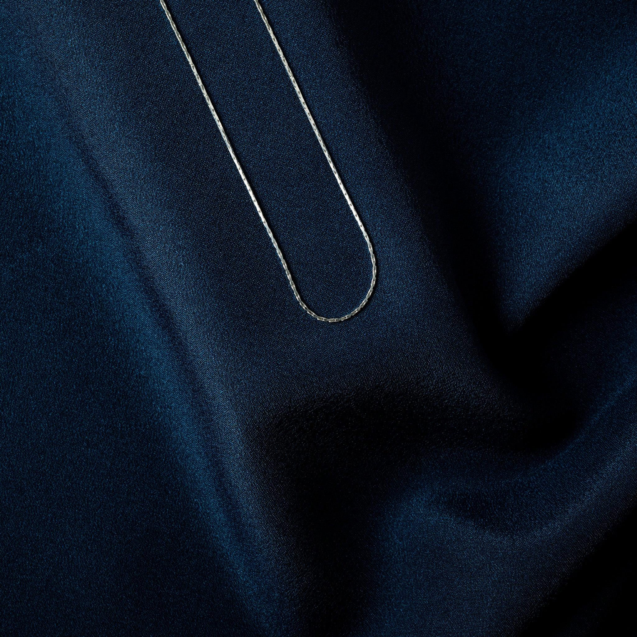 Round spring ring clasp with a thumb tab lever on a fine silver chain, macro