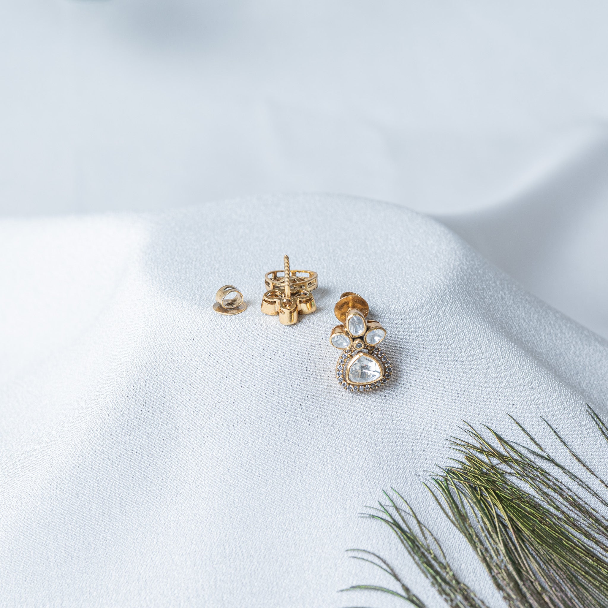 Close view of the trillion uncut stone ringed by round CZ at the base of the earring