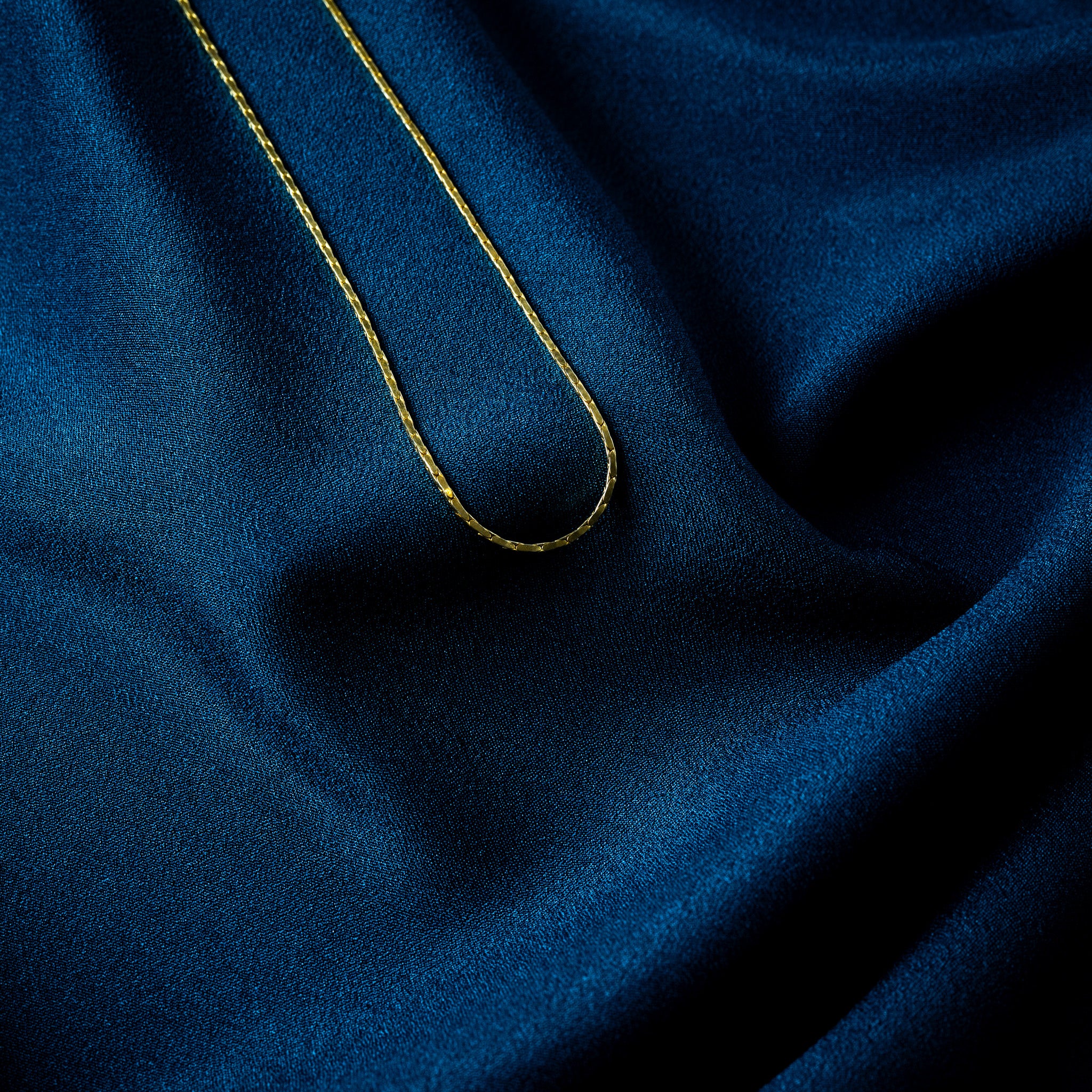Notch at every joint on a gold plated flat bar link chain, close crop