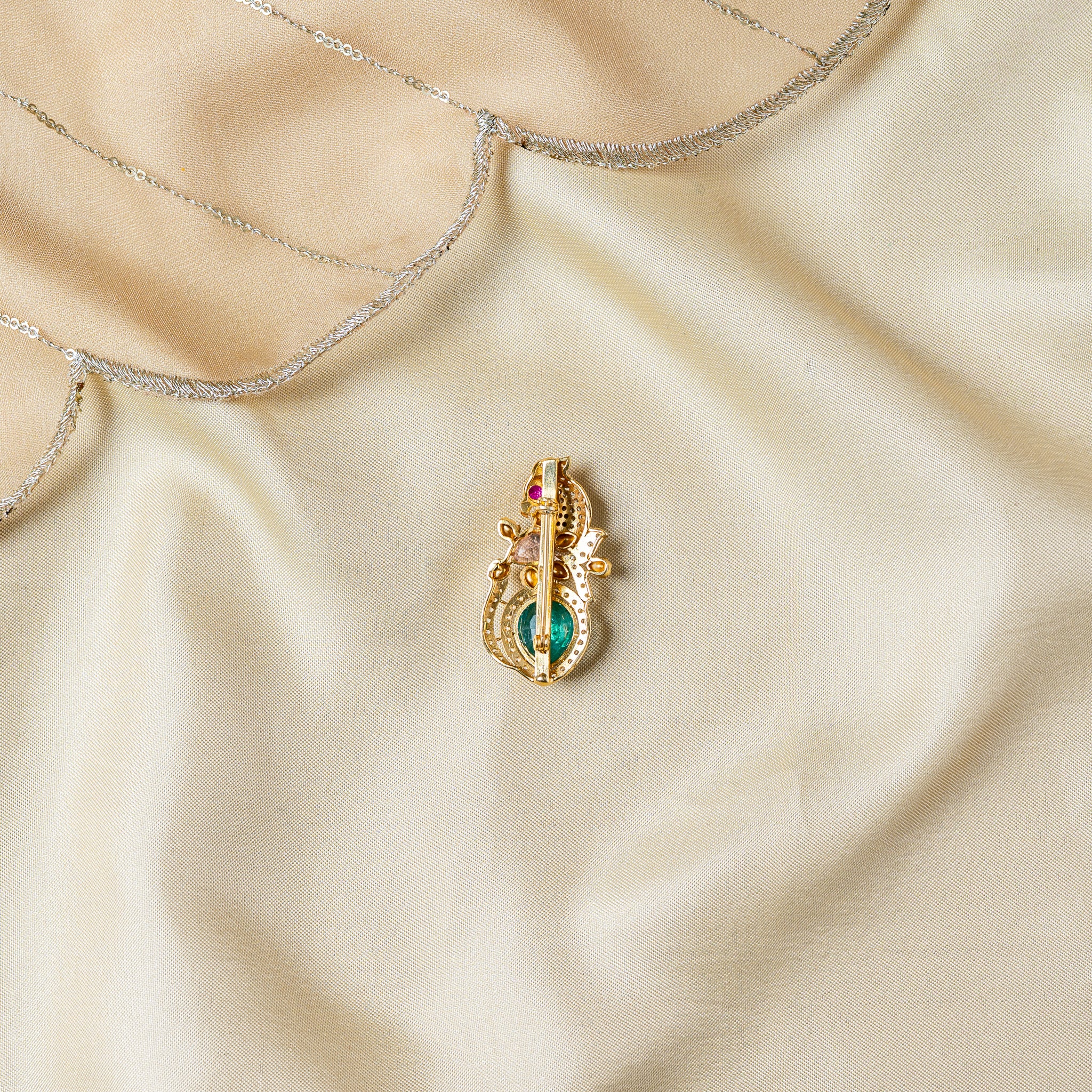 Close crop of the back of the peacock brooch showing the rolled hinge and the pin bar