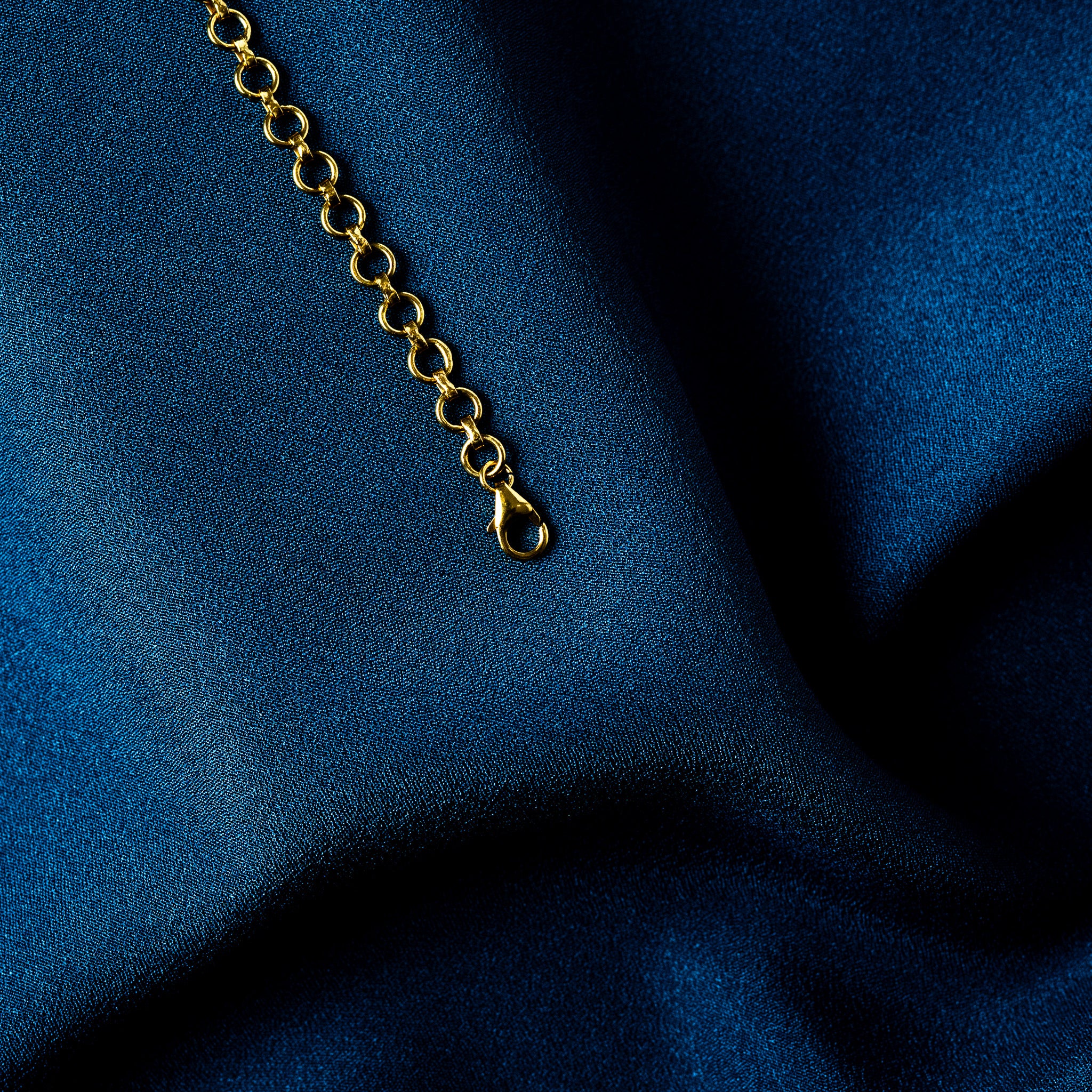 Macro of the lobster clasp on a gold plated round link back chain