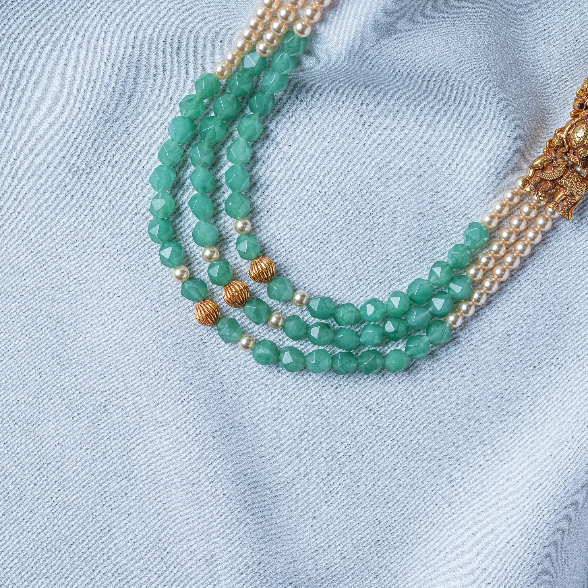 Fluted gold melon beads at the centre front between faceted mint green beads