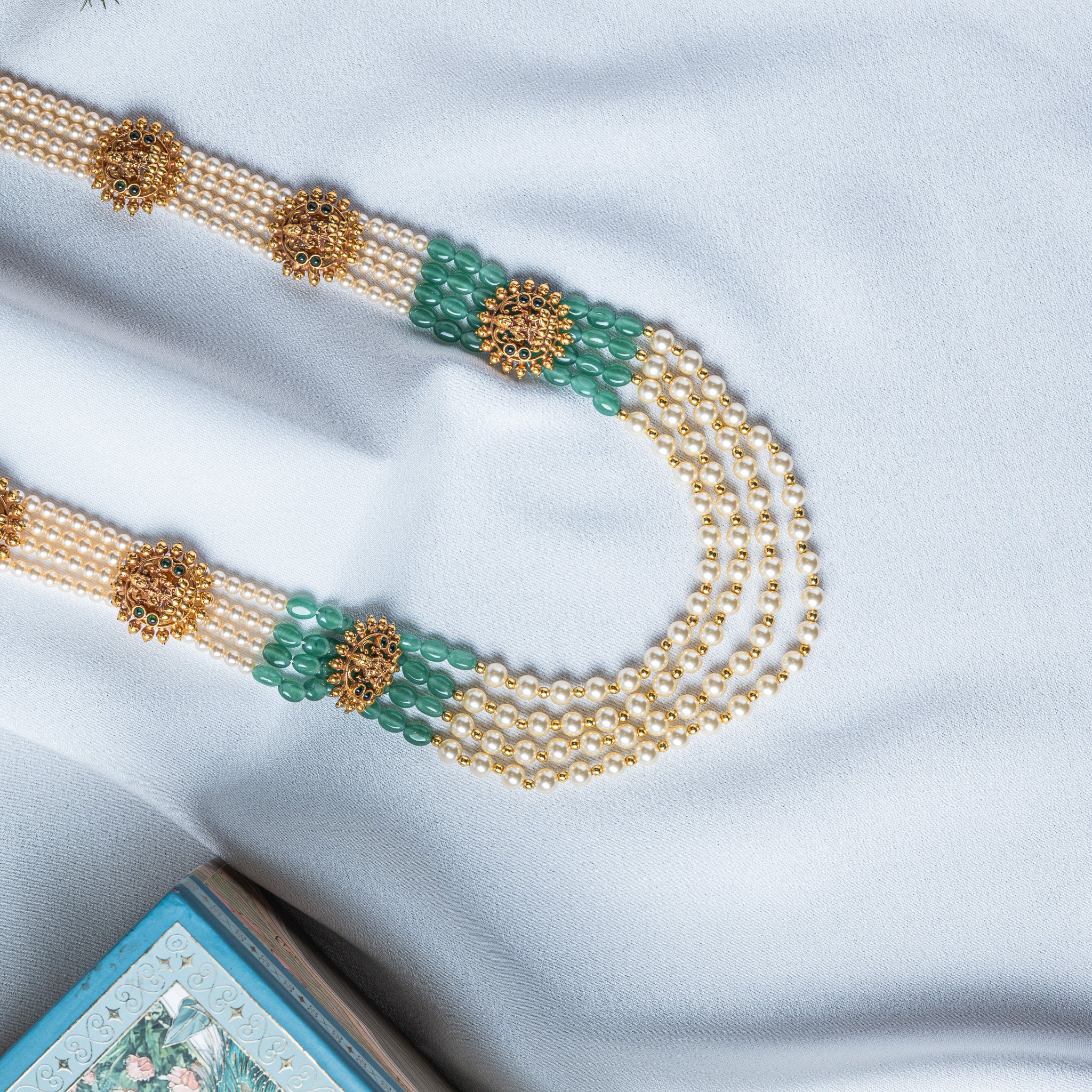 Side view showing sections of oval green beads between the pearl strands