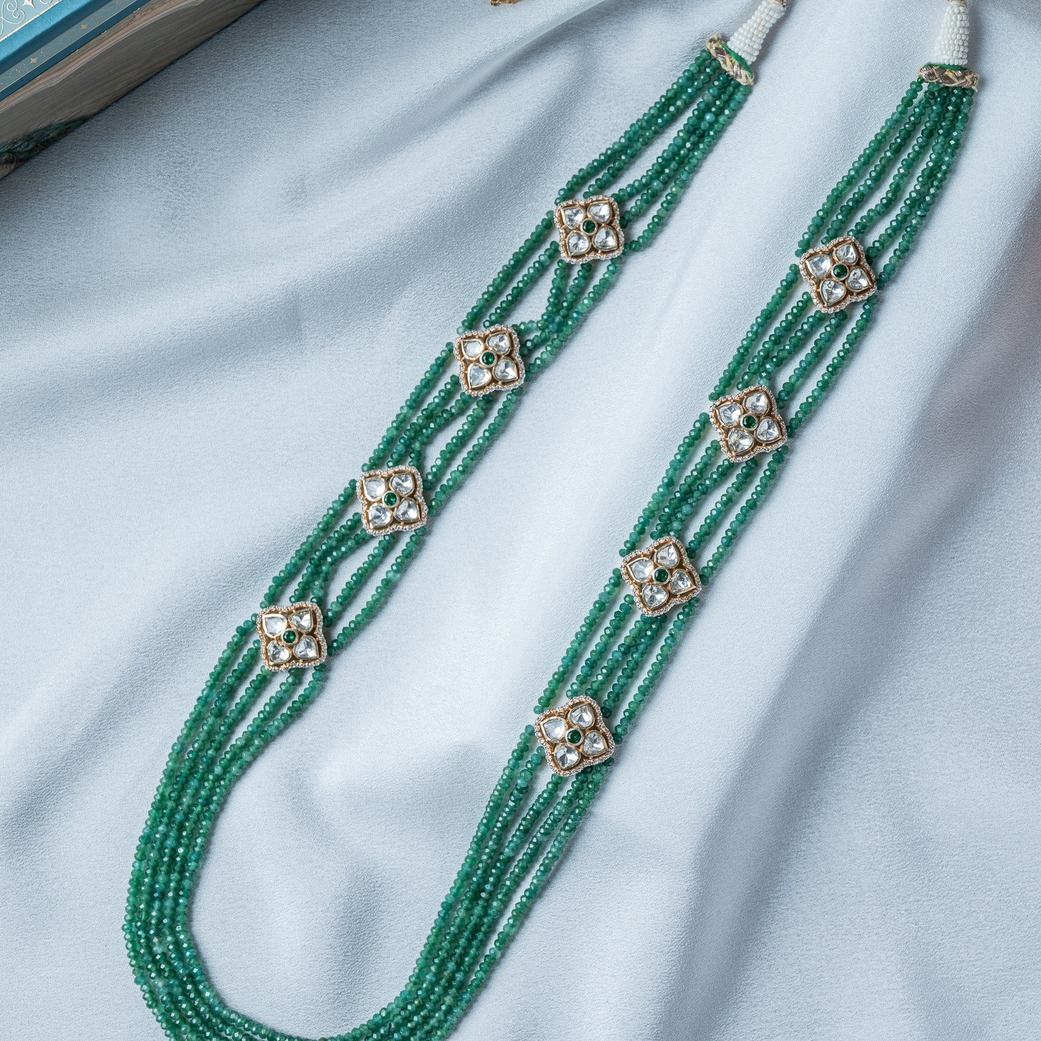 Side view of the green bead necklace showing the strands gathered into gold end caps