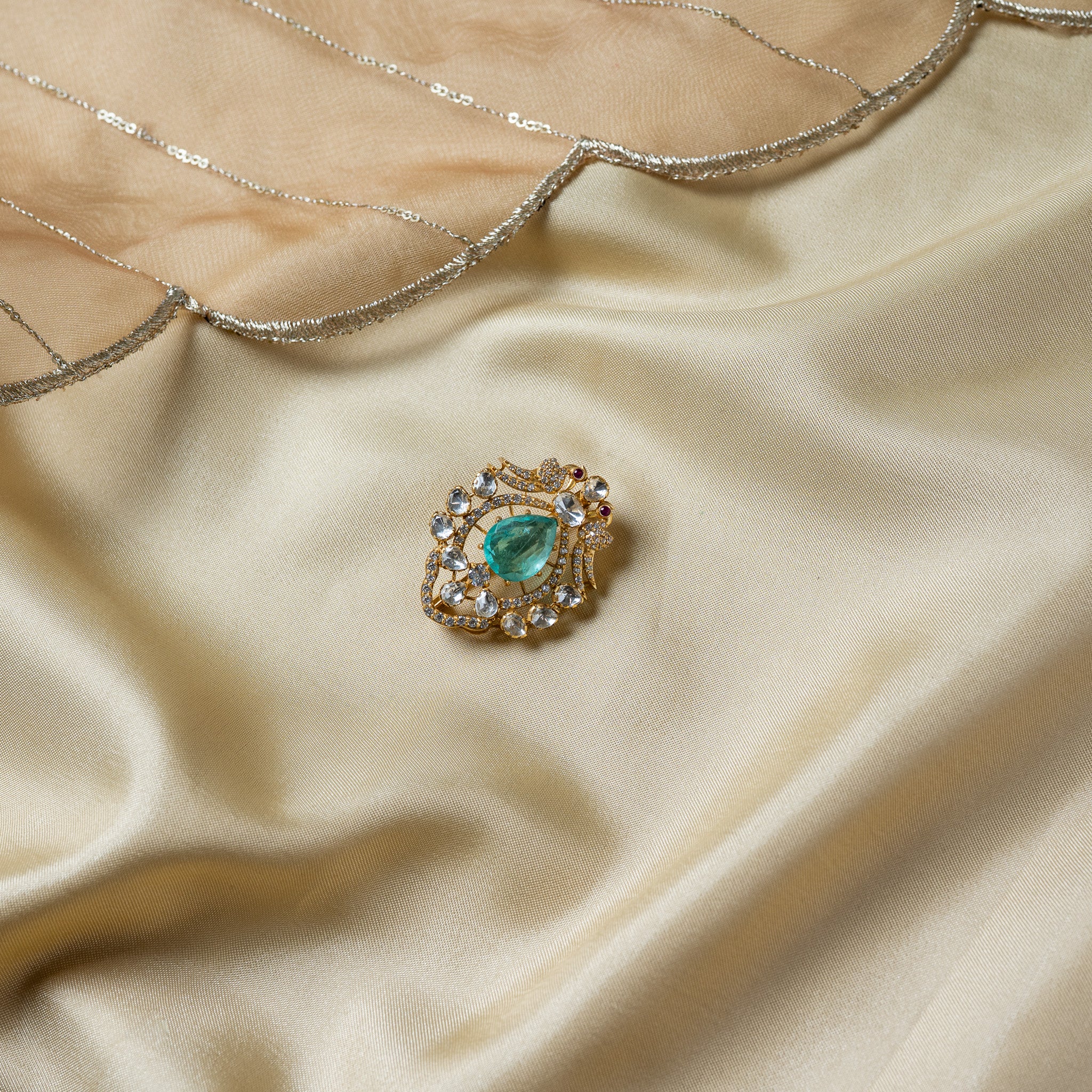 Side view of the lotus bud brooch showing the depth of the polki ring and the claw set green stone