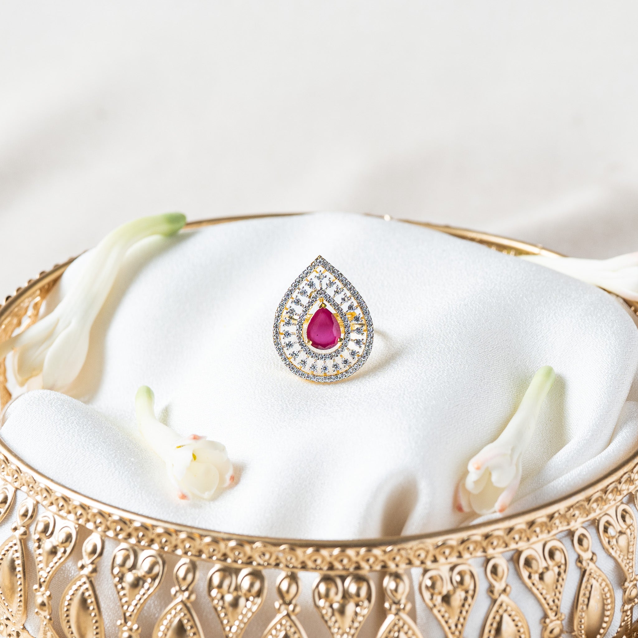 Close front view of the scalloped CZ halo around the magenta pink pear cut stone