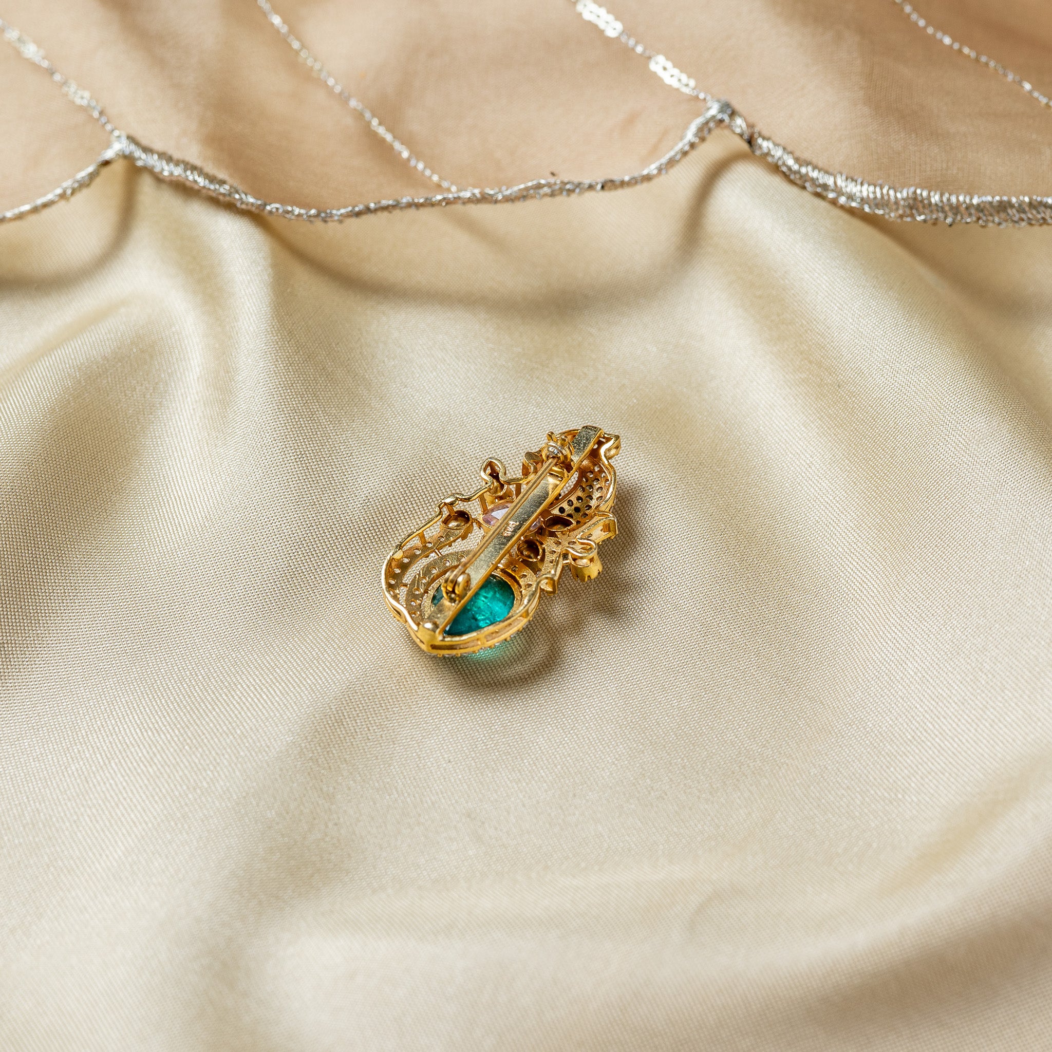 Full reverse of the peacock brooch with the pin bar running its length to the hook catch