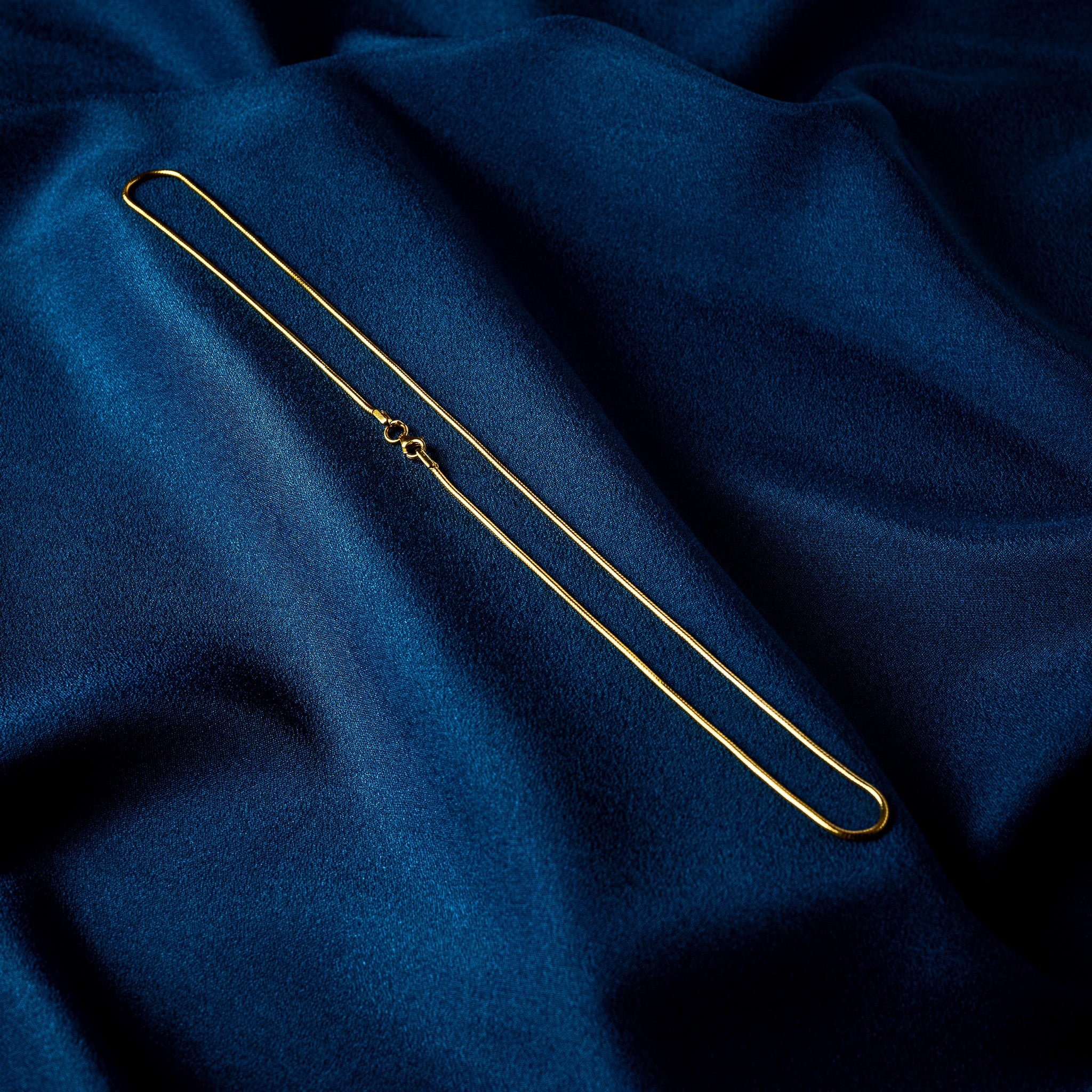 Full 20 inch length of a gold plated snake chain laid out flat