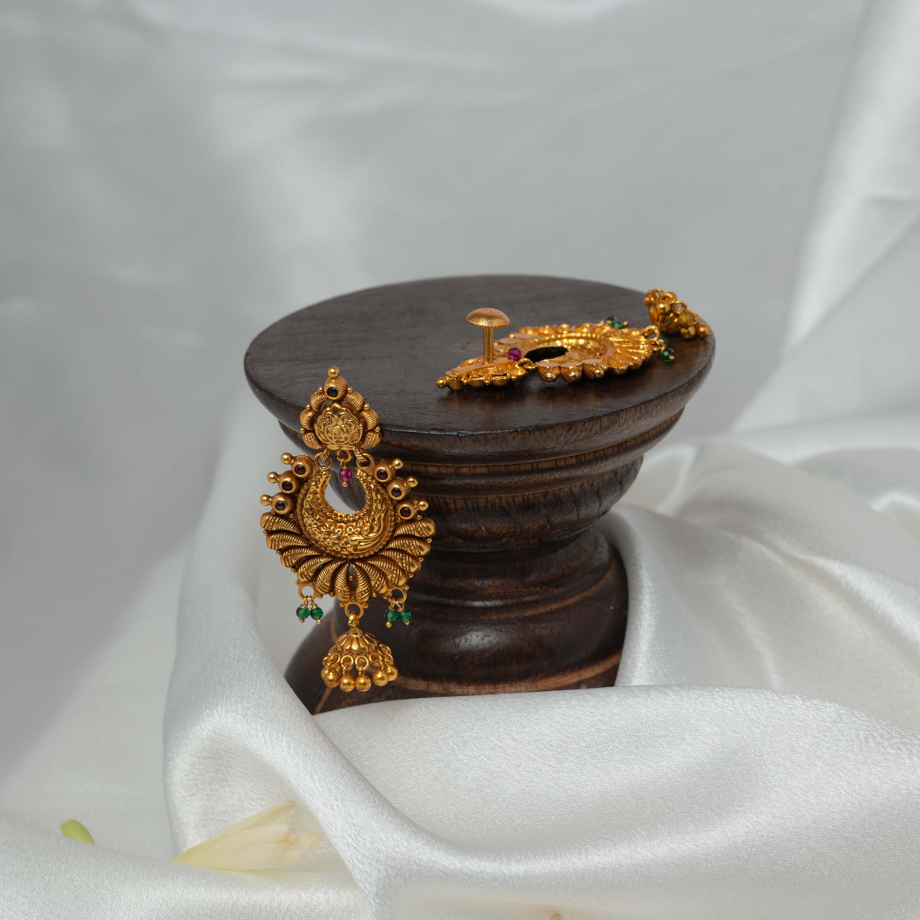 Three quarter view of the small gold jhumka and green bead drops under the peacock chand bali