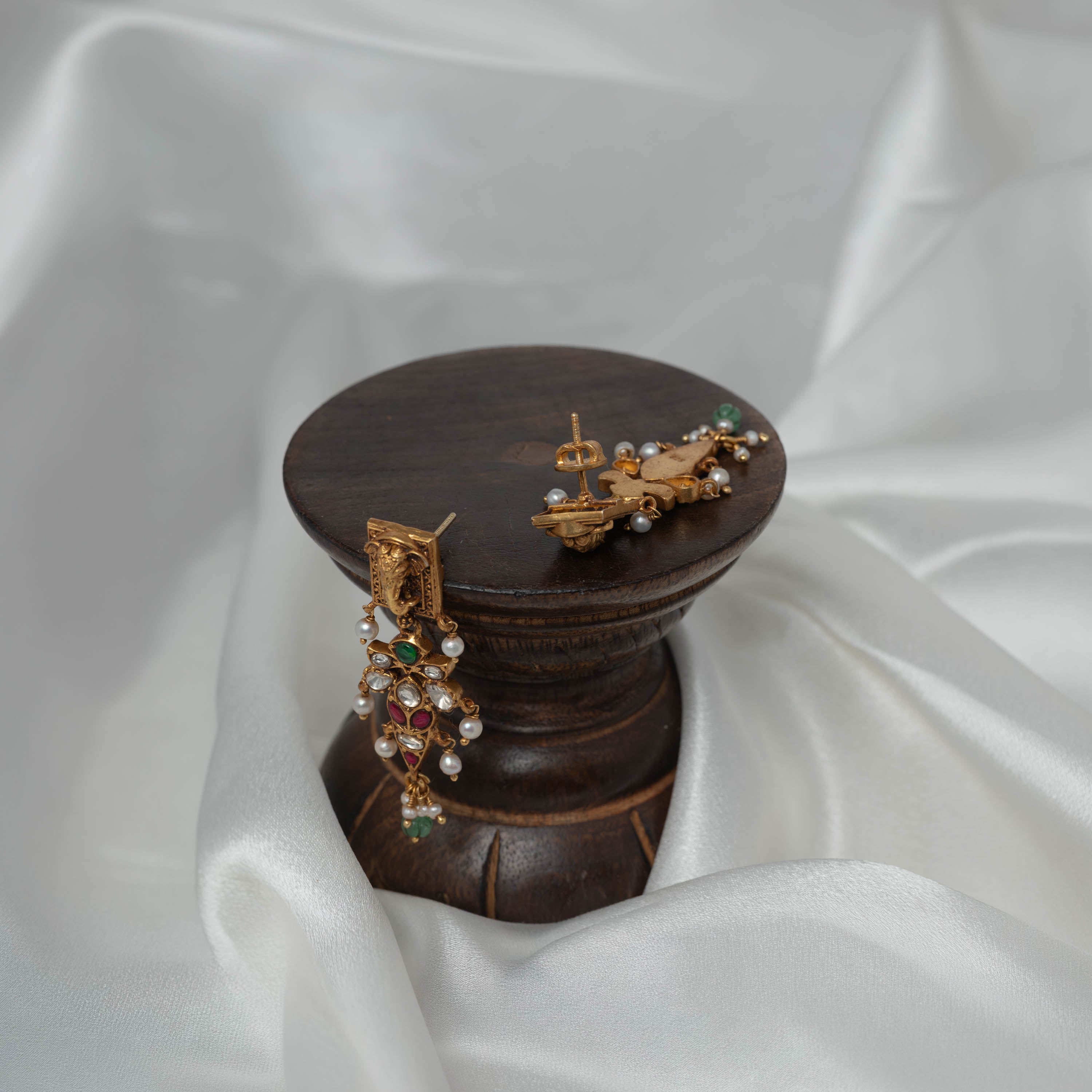 Elephant head top bar above the kundan cascade in antique gold, angled view