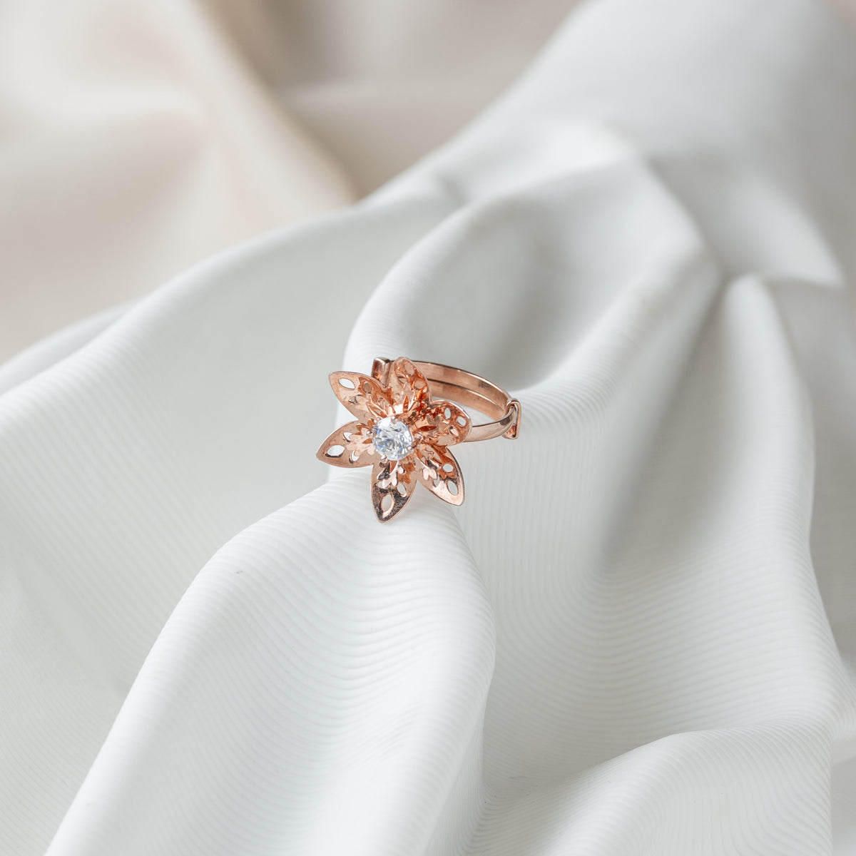 Angled view of the six petal flower ring, pierced petals around the CZ, rose gold plated 925 silver