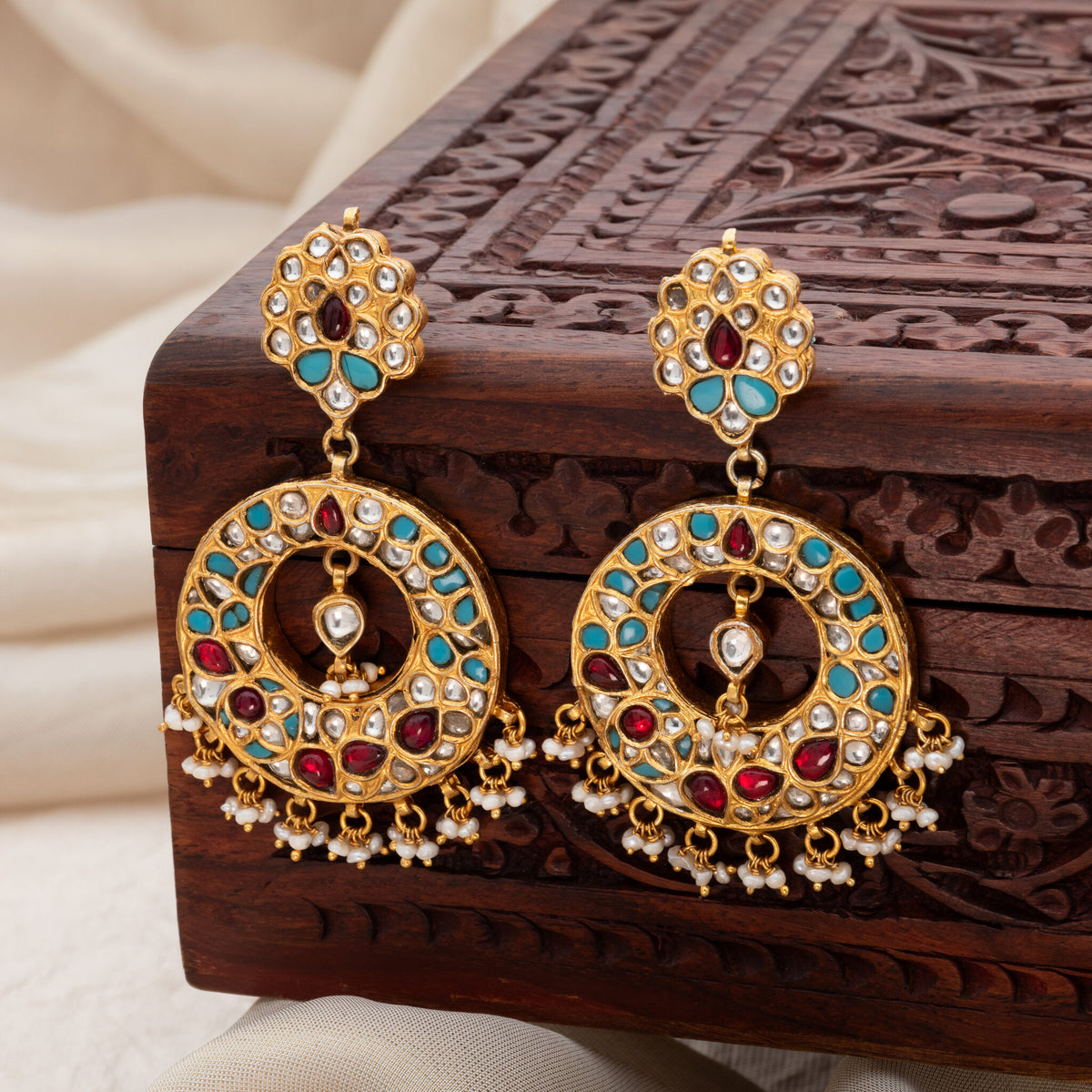 Pair of kundan chand balis on a carved box, turquoise and red tiles with freshwater pearl clusters