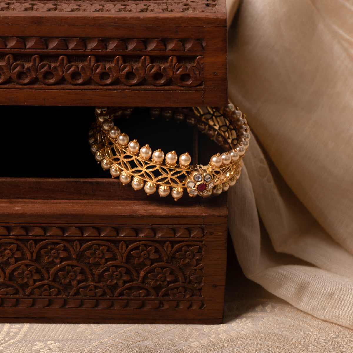 Seed pearl rows along both rims of the jaali kada, seen at an angle in gold plated 925 silver