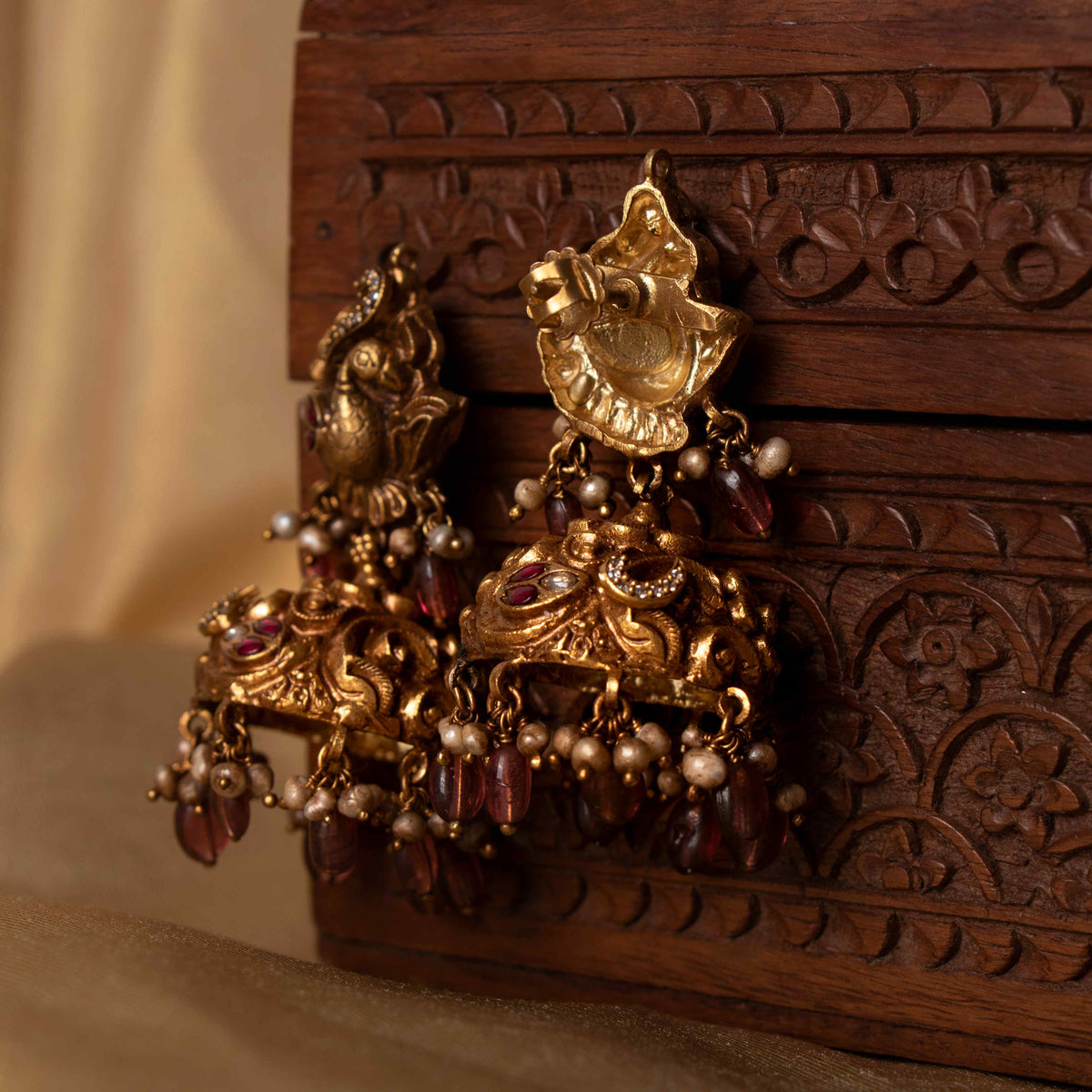 Nakaashi peacock jhumkas with carved dome, maroon bead and grey pearl drops, antique gold plated silver.