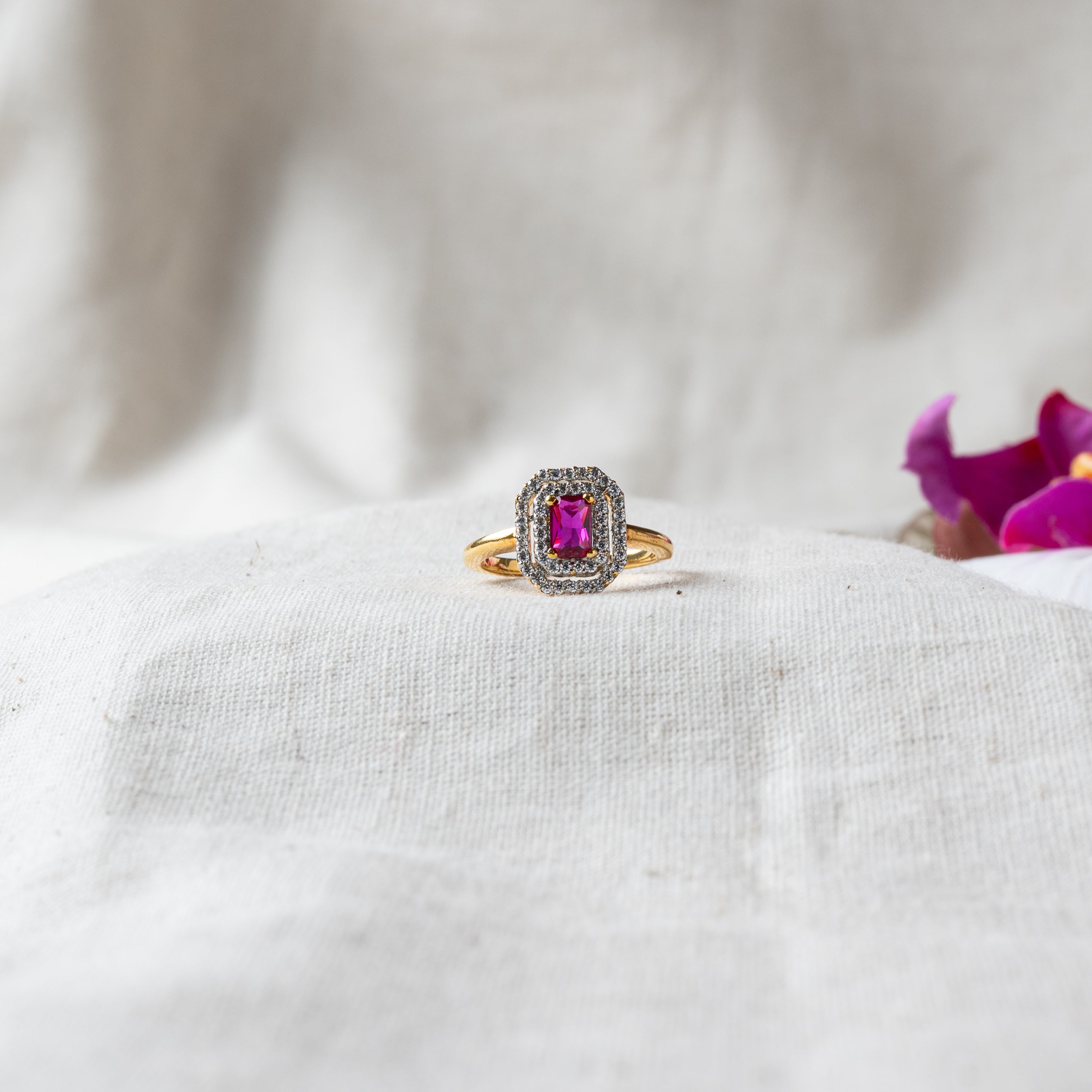 Emerald cut ruby ring framed by a double CZ halo in gold plated 925 silver