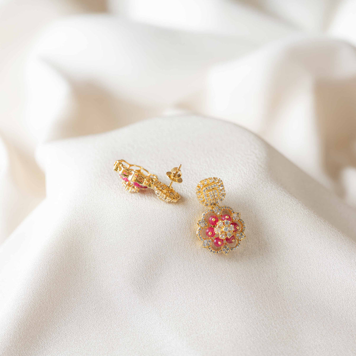 Detail of the square CZ pave top above an open flower set with red beads in gold plated silver