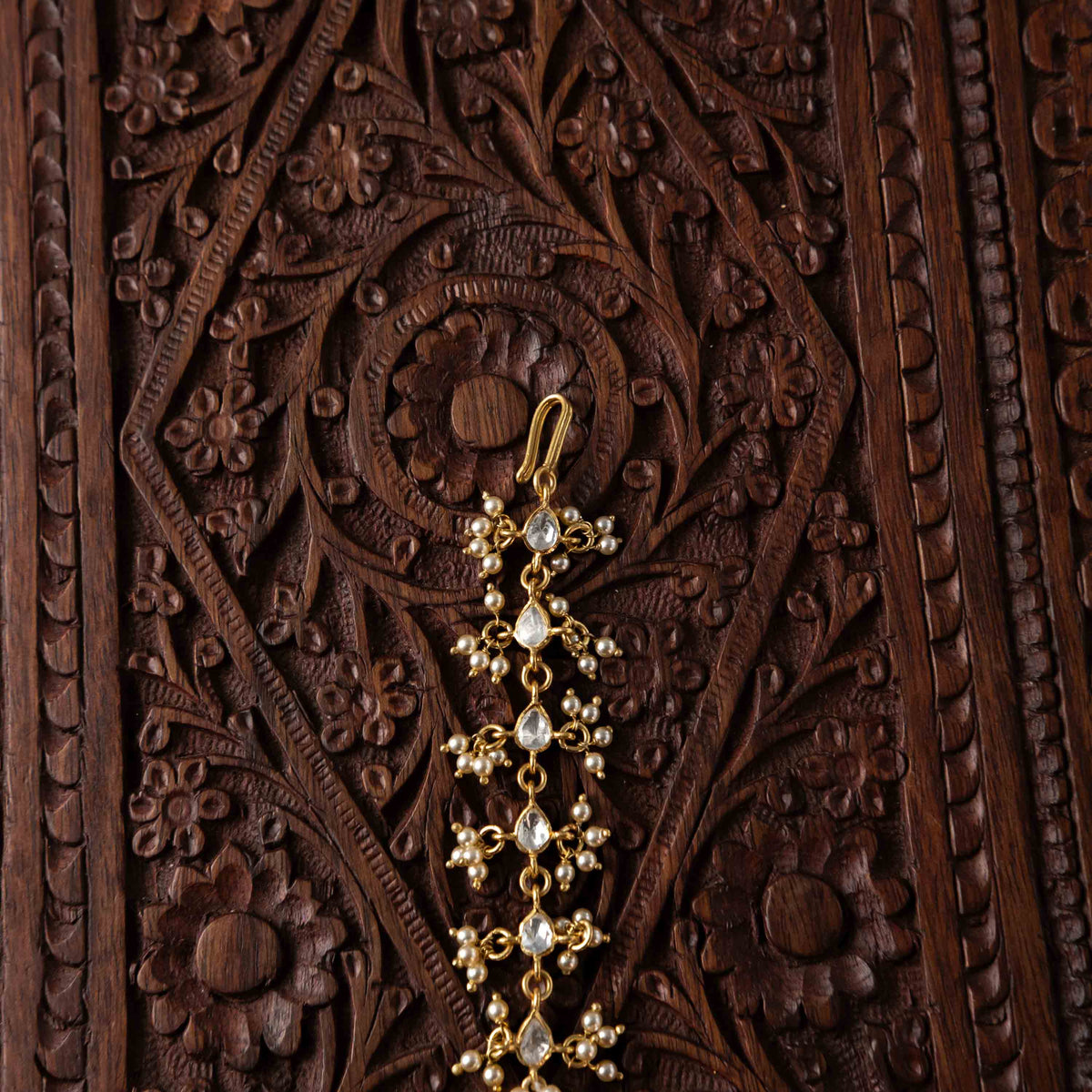 Fish hook fitting above the tiered polki maangtika with its seed pearl drops in 925 silver