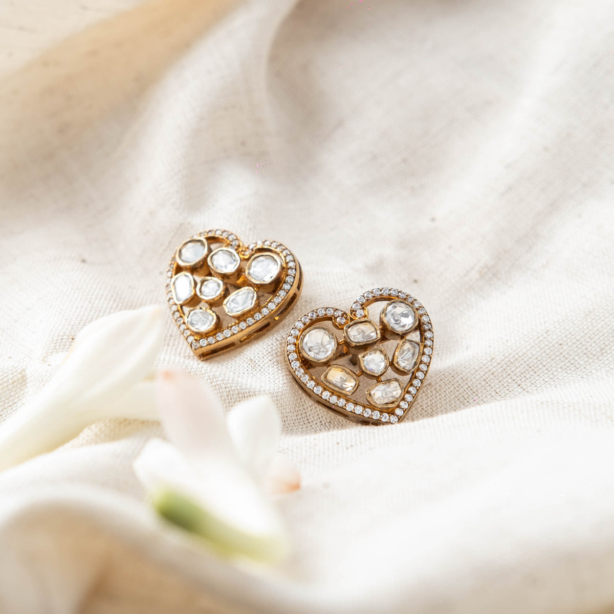 Pair of heart stud earrings at an angle, uncut polki set in blackened gold inside a CZ edge