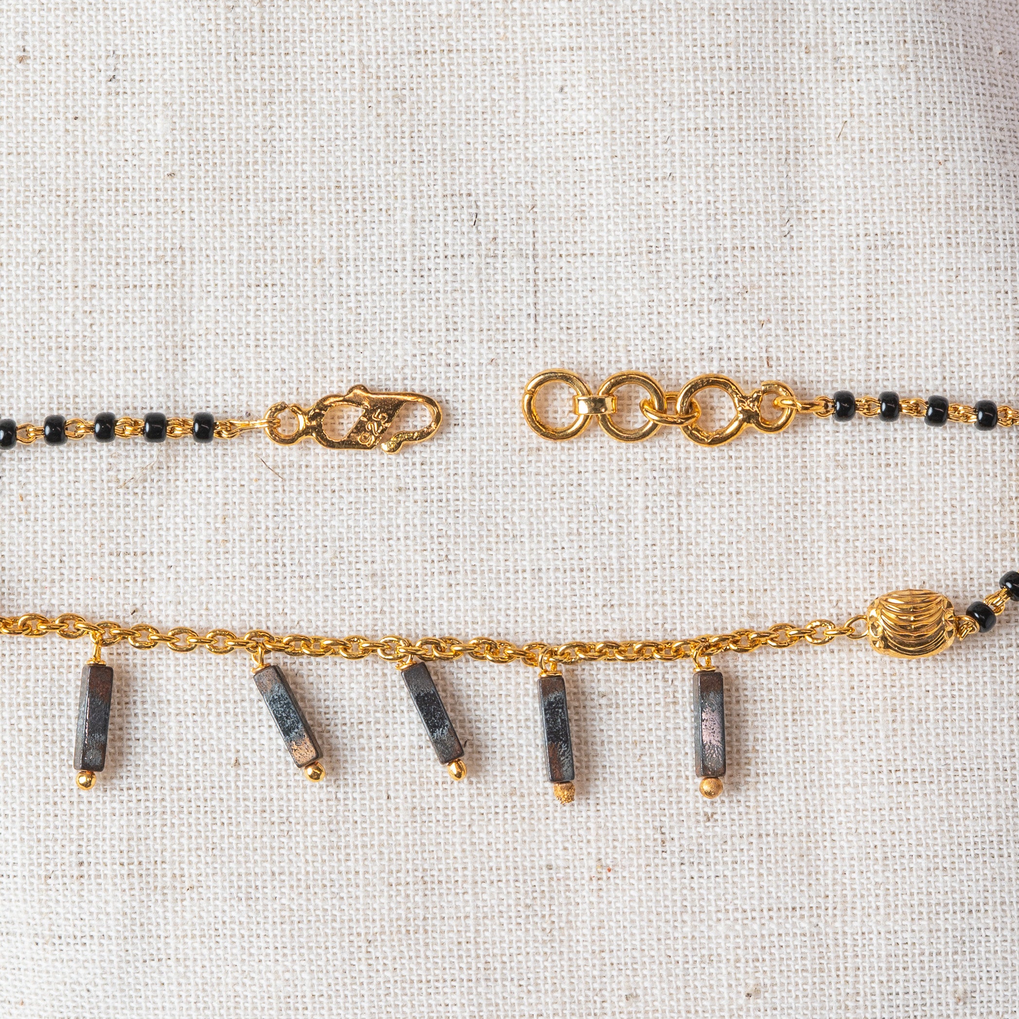 Black bead bracelet curved to show the fluted bead and charm drops, gold plated 925 silver