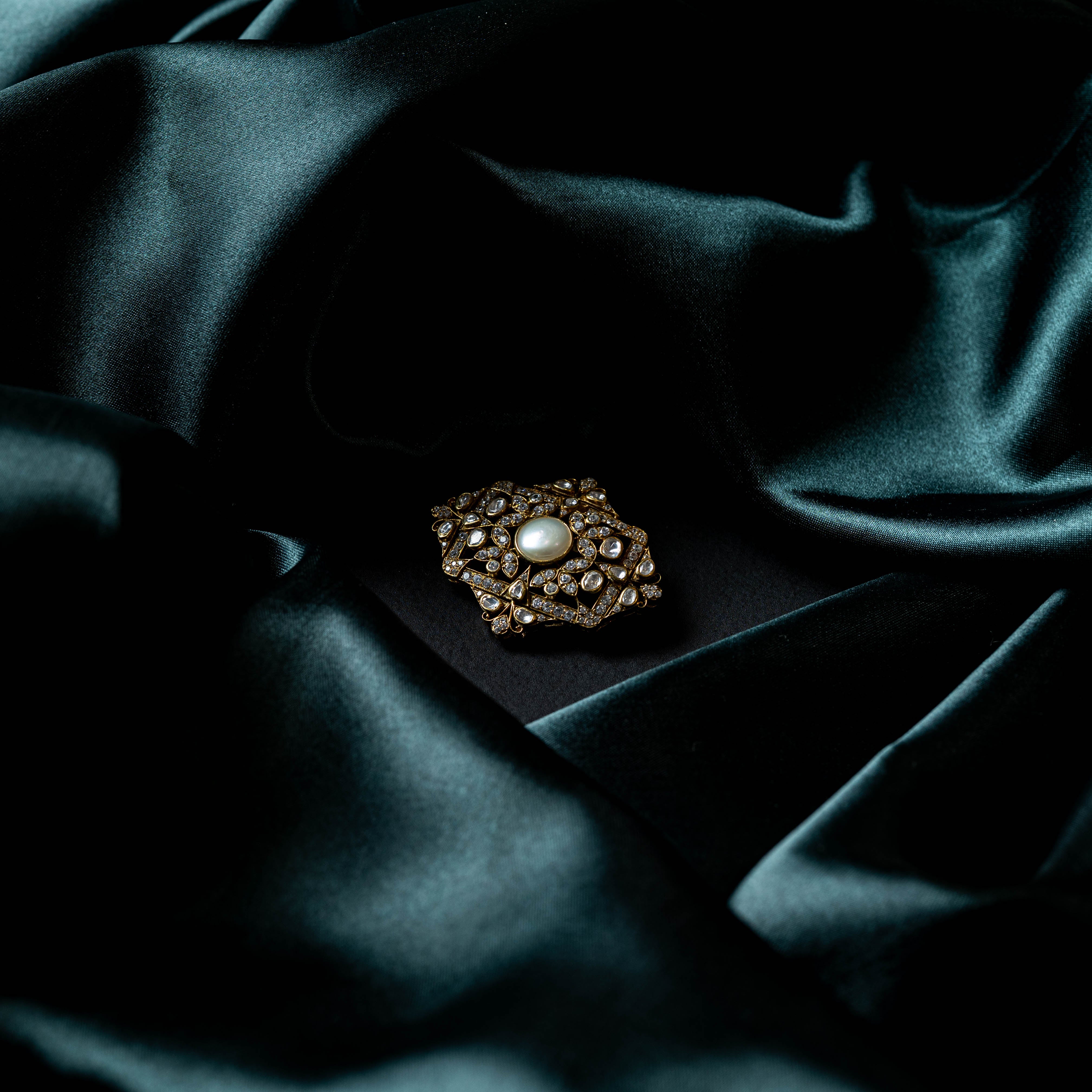 Angled view of the polki brooch showing the raised frame and shell pearl centre in 925 silver