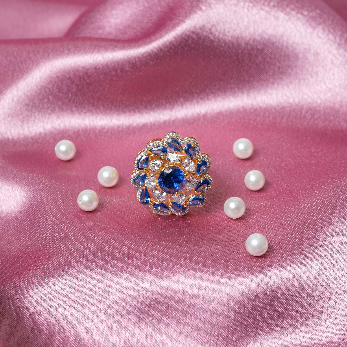 Deep blue round stone ringed by blue pear petals and white CZ on a gold plated 925 silver ring