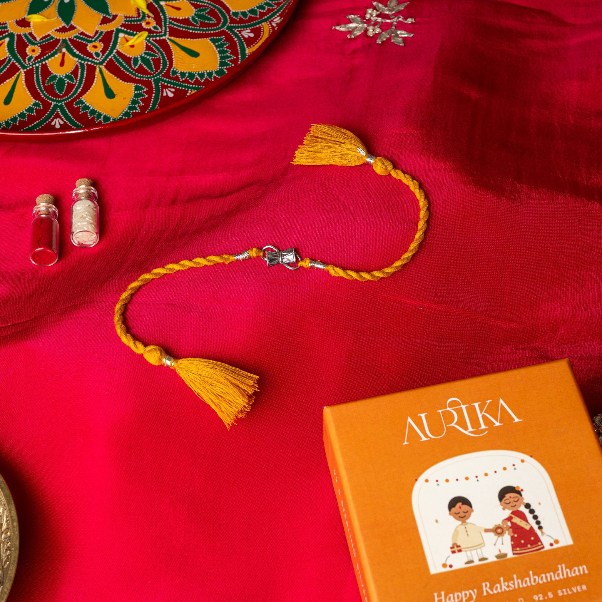 Waisted damaru drum with a strap loop in 925 silver on a red twisted silk rakhi cord with tassels