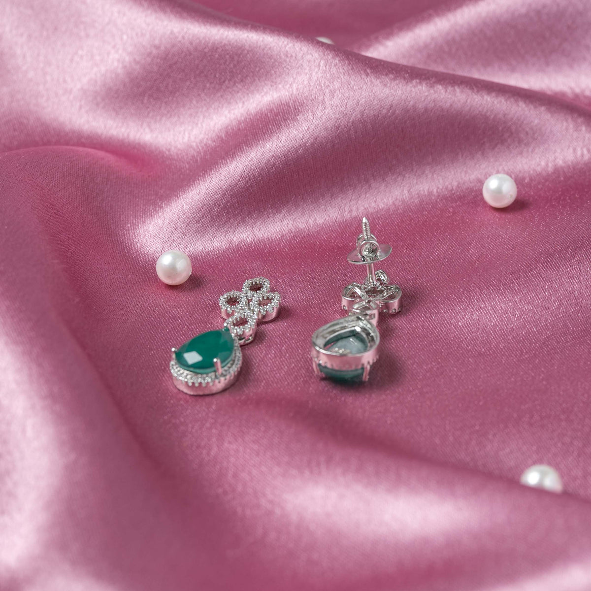 Angled view of the open CZ link frames above green teardrop drops in rhodium finish silver