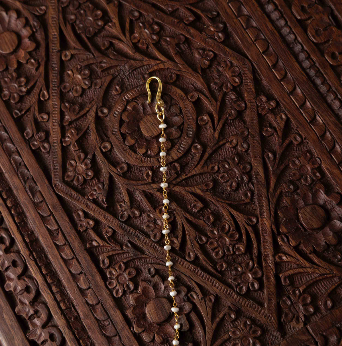 Fish hook and pearl chain at the top of the gold plated polki maangtika in 925 silver