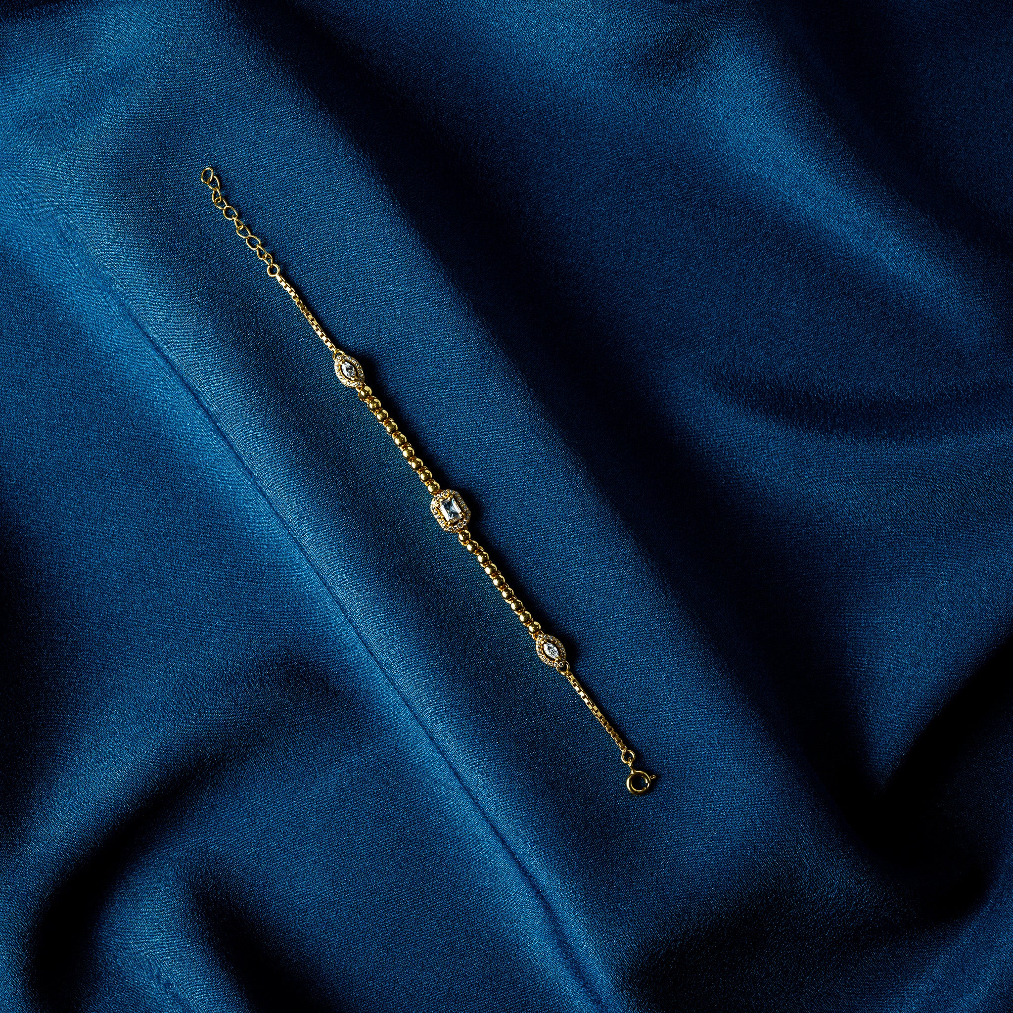 Three station CZ bracelet in gold plated 925 silver, a step cut rectangle between two marquise halos