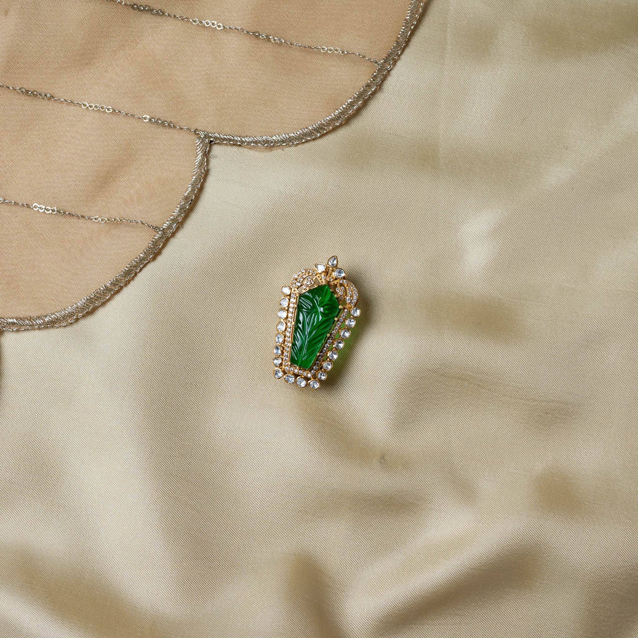 Hand carved green stone brooch with a leaf pattern bordered by uncut polki, gold plated 925 silver