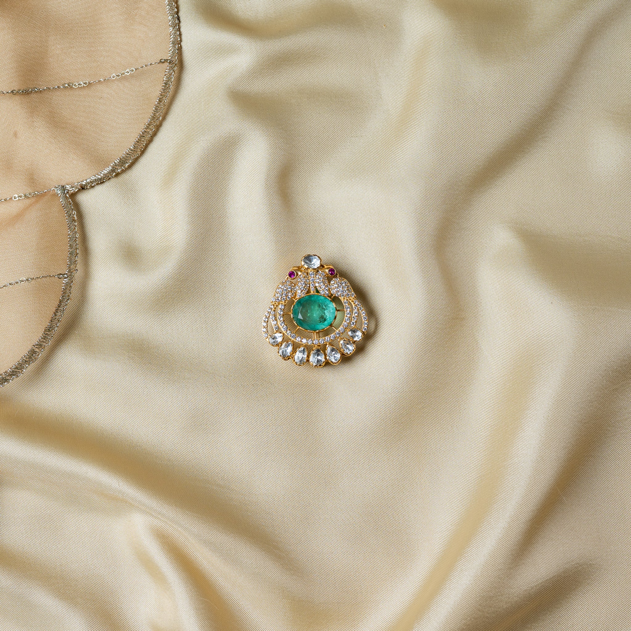 Paisley scroll brooch with a large oval green centre and a fringe of uncut polki in gold plated 925 silver