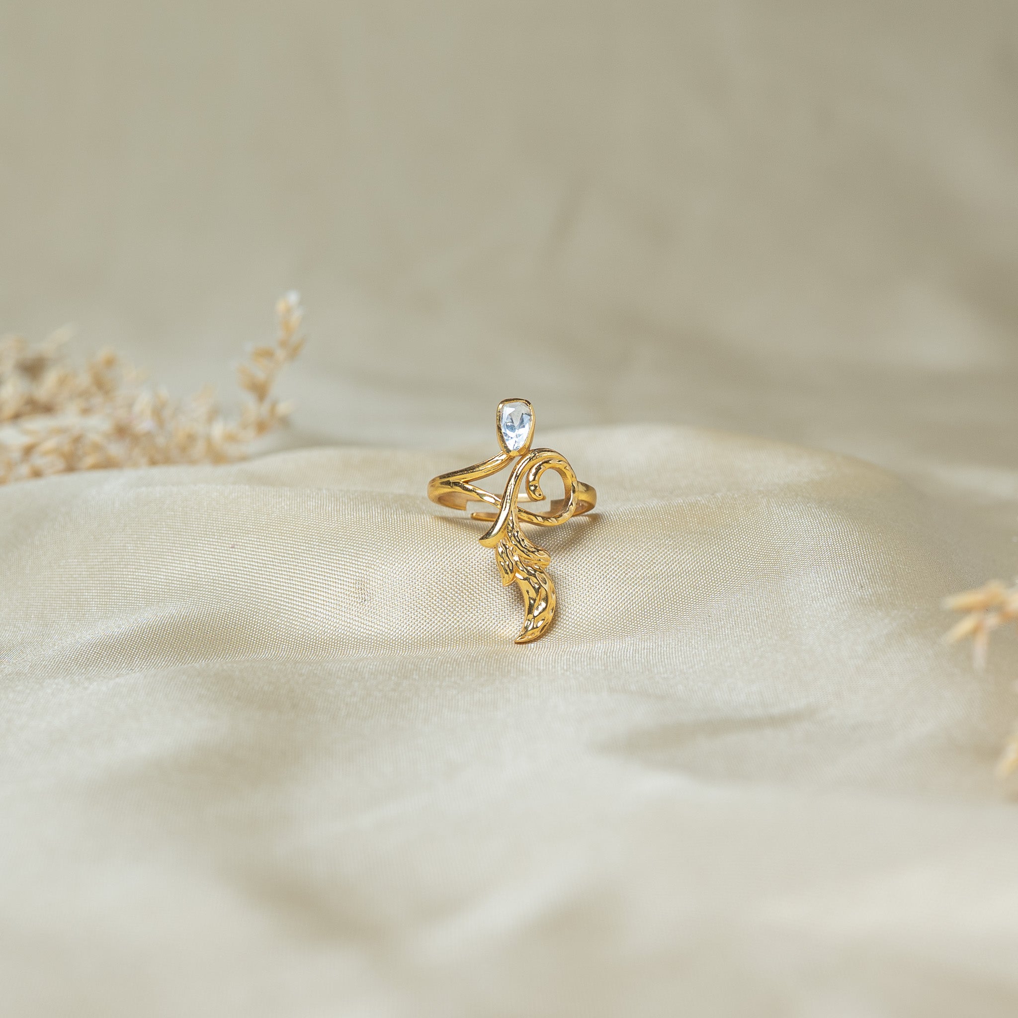 Uncut pear polki ring on a gold vine with a long chased leaf trailing down the finger