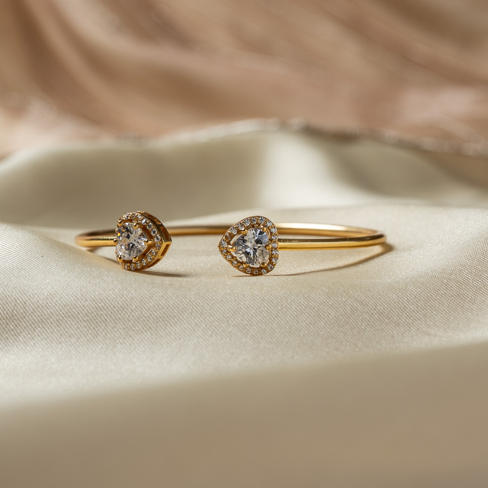 Close view of one heart cut CZ held in four gold claws inside a halo of small round CZ