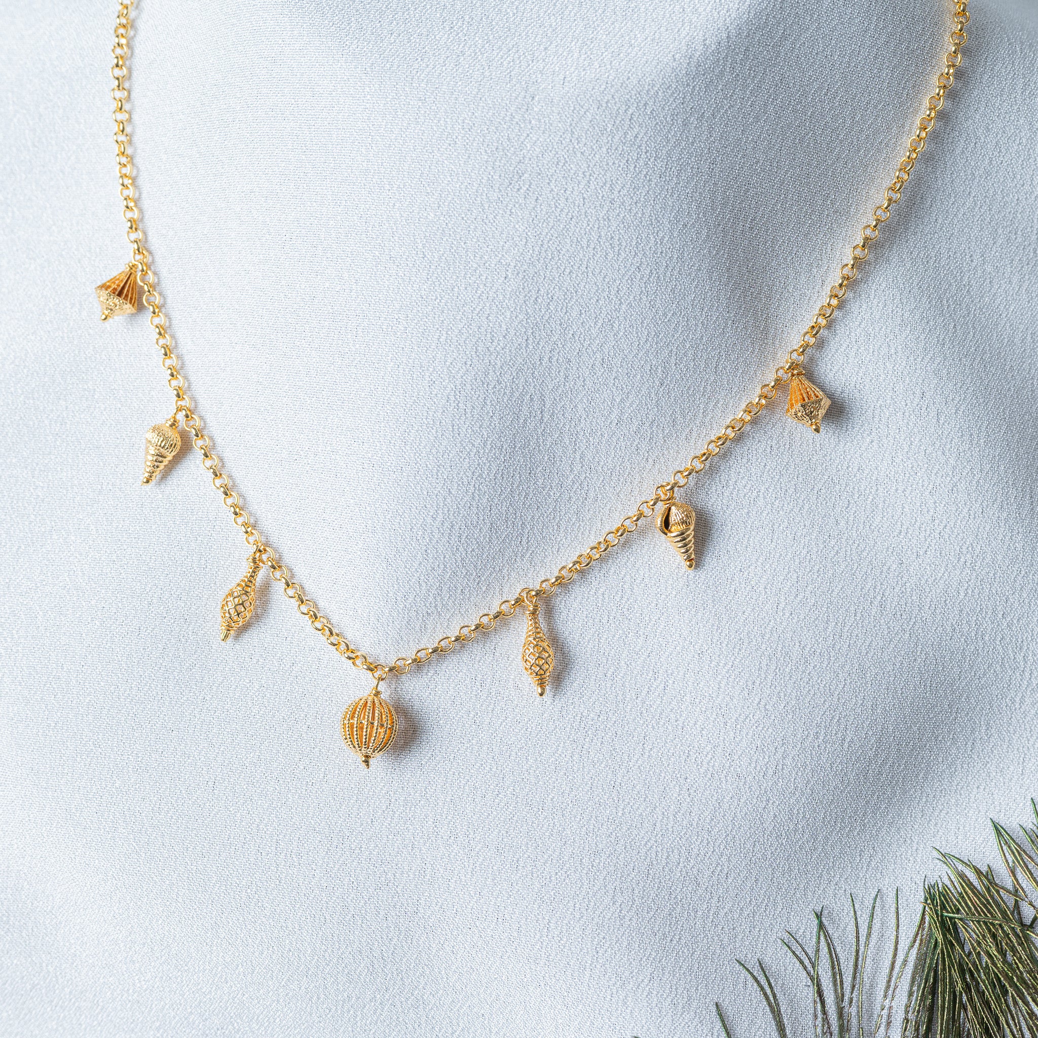 Close crop on the ribbed jaali lantern bead and the grains of gold worked over the charms