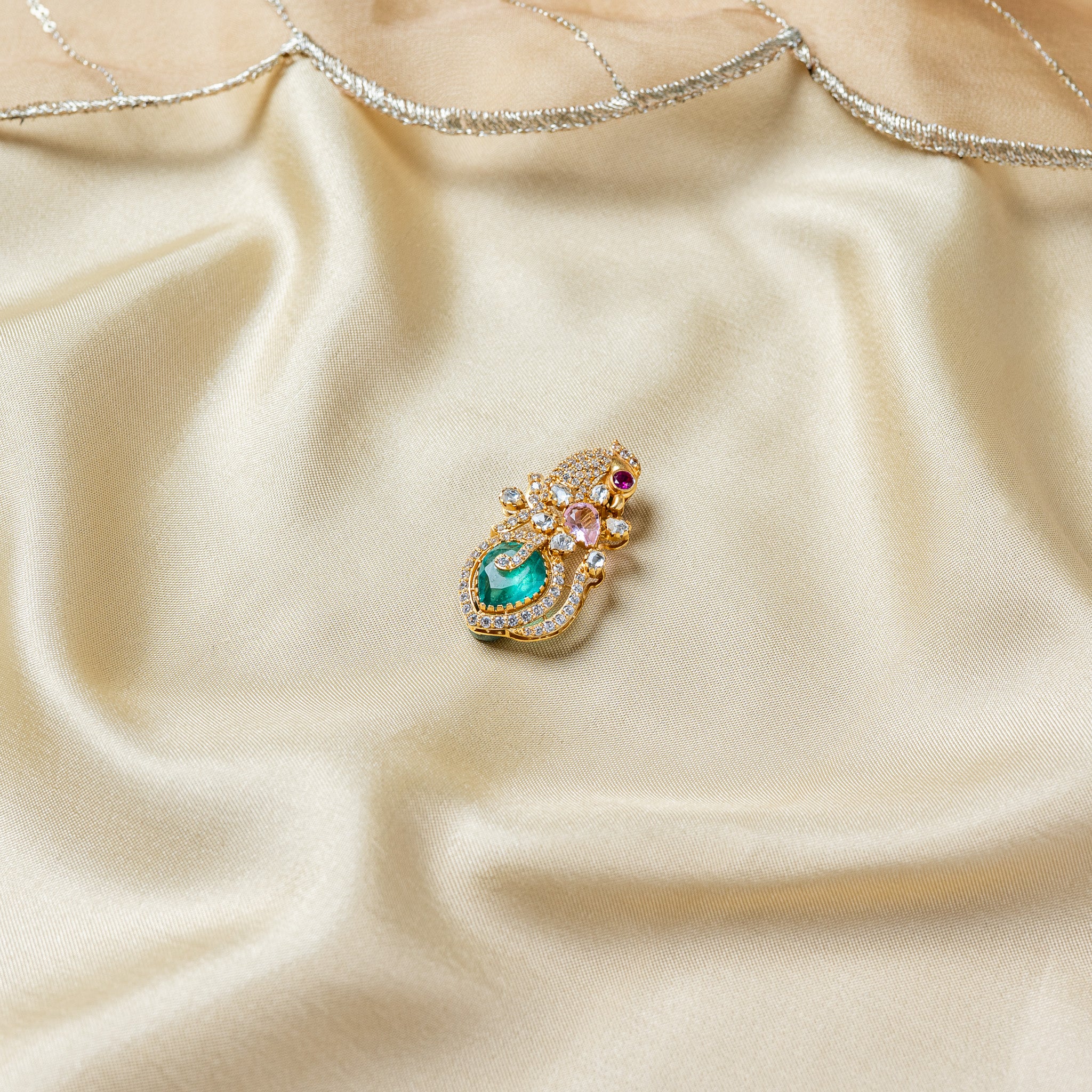 Angled view of the peacock brooch showing the crested pave body and the curl of the plume