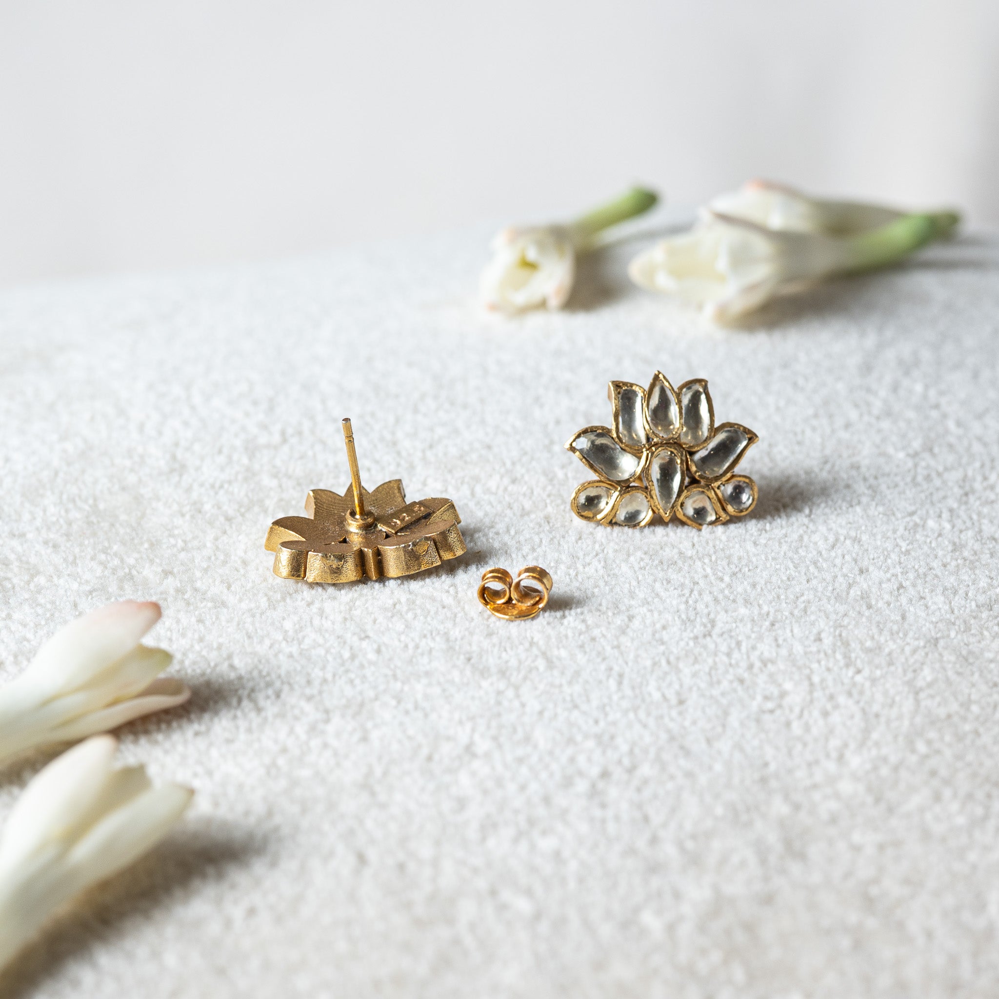 Back of a white kundan lotus stud showing the smooth post and the gold push back beside it