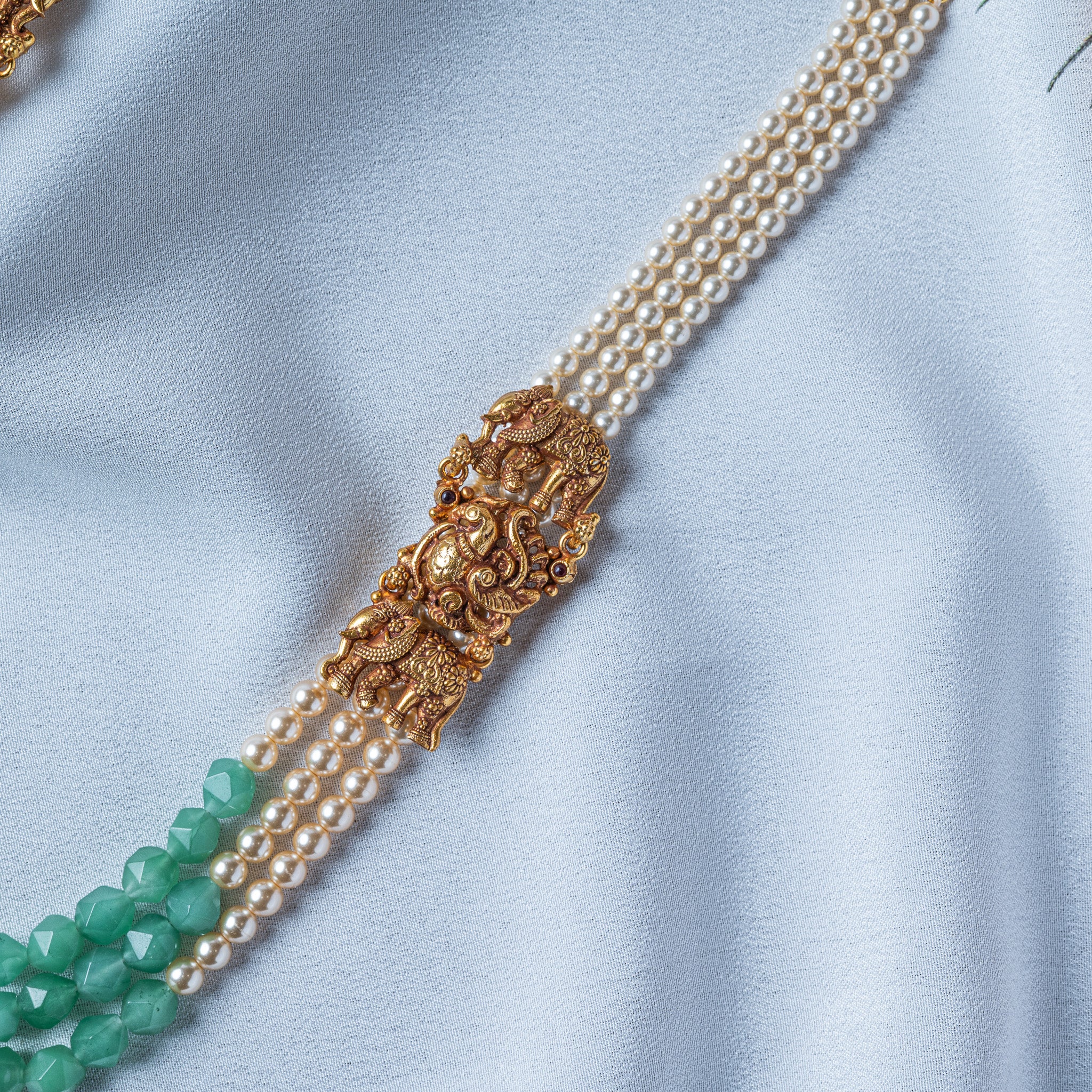 Elephant side piece close up, a large elephant flanked by two smaller ones in beaded howdah saddles