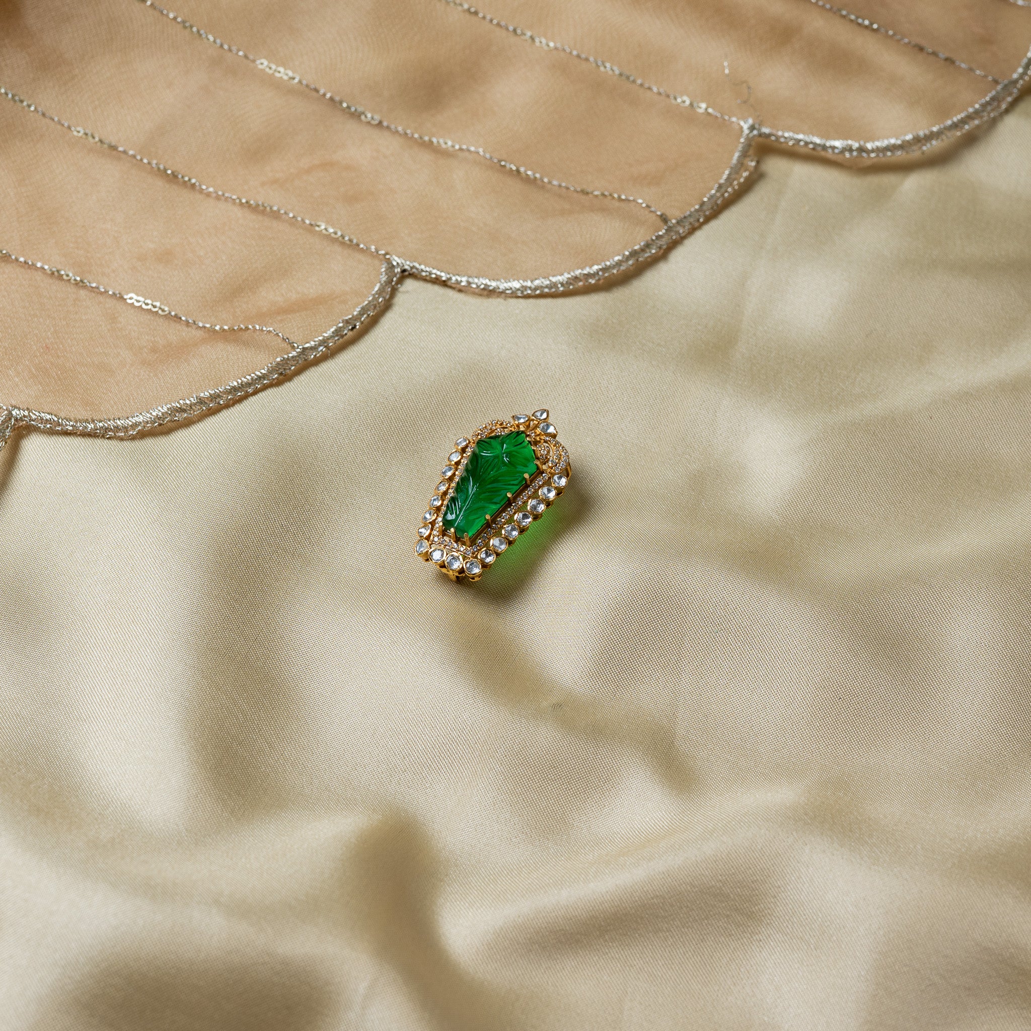 Side view showing the translucent carved green stone and the polki sweep up the right edge