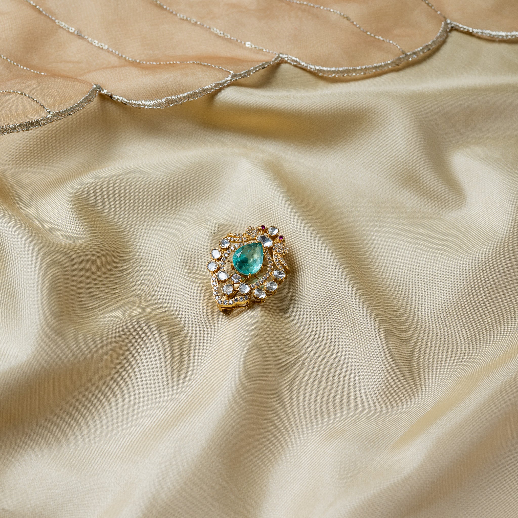 Front view of the lotus brooch with twin swept pave wings tipped in red either side of the polki frame