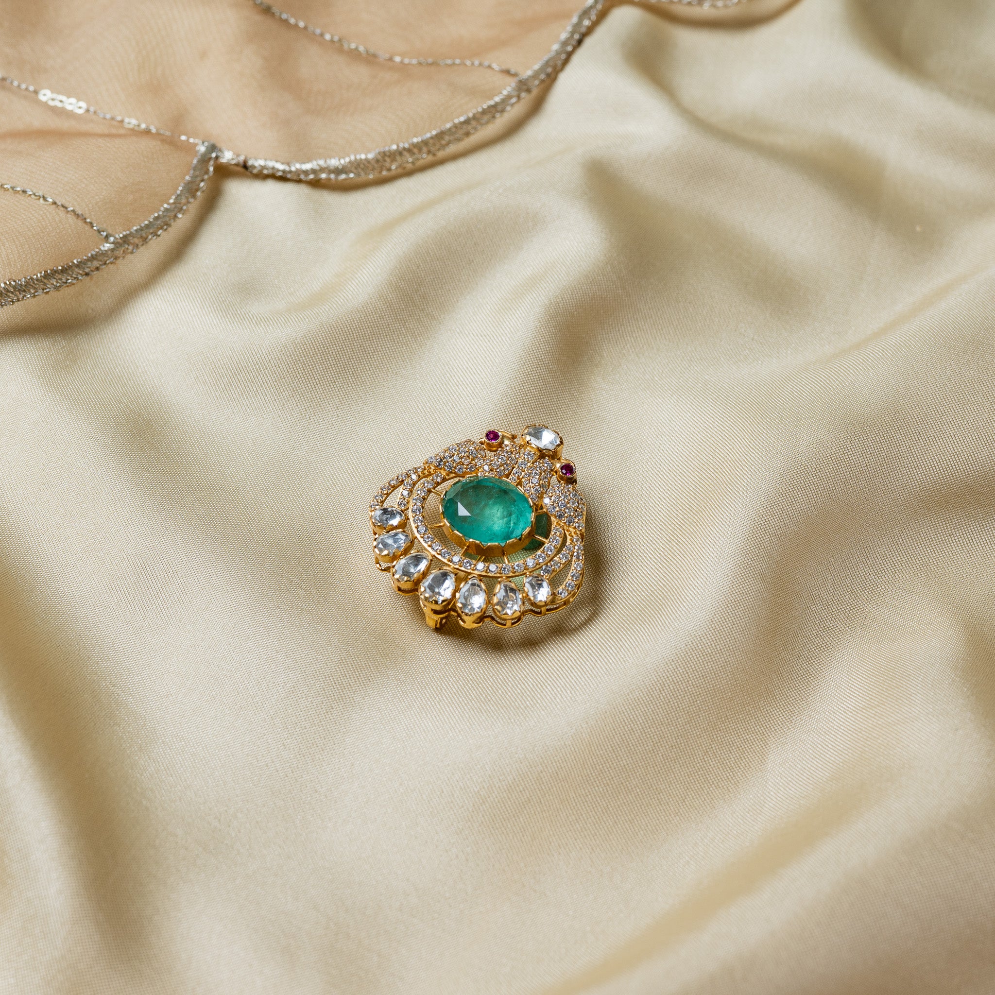 Close view of the oval green centre stone ringed by double pave and topped with a single uncut polki