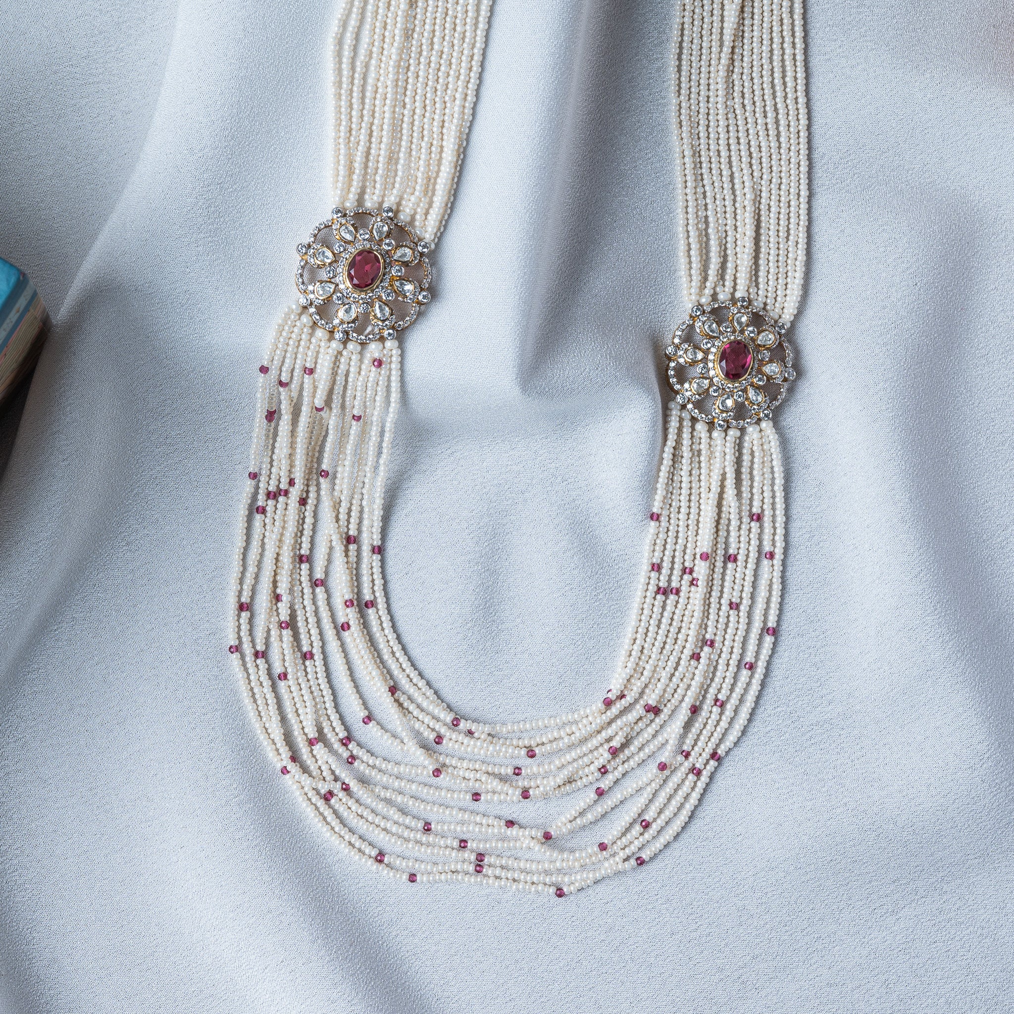 Shoulder rosette close up, an oval red stone ringed with uncut white stones in gold foil