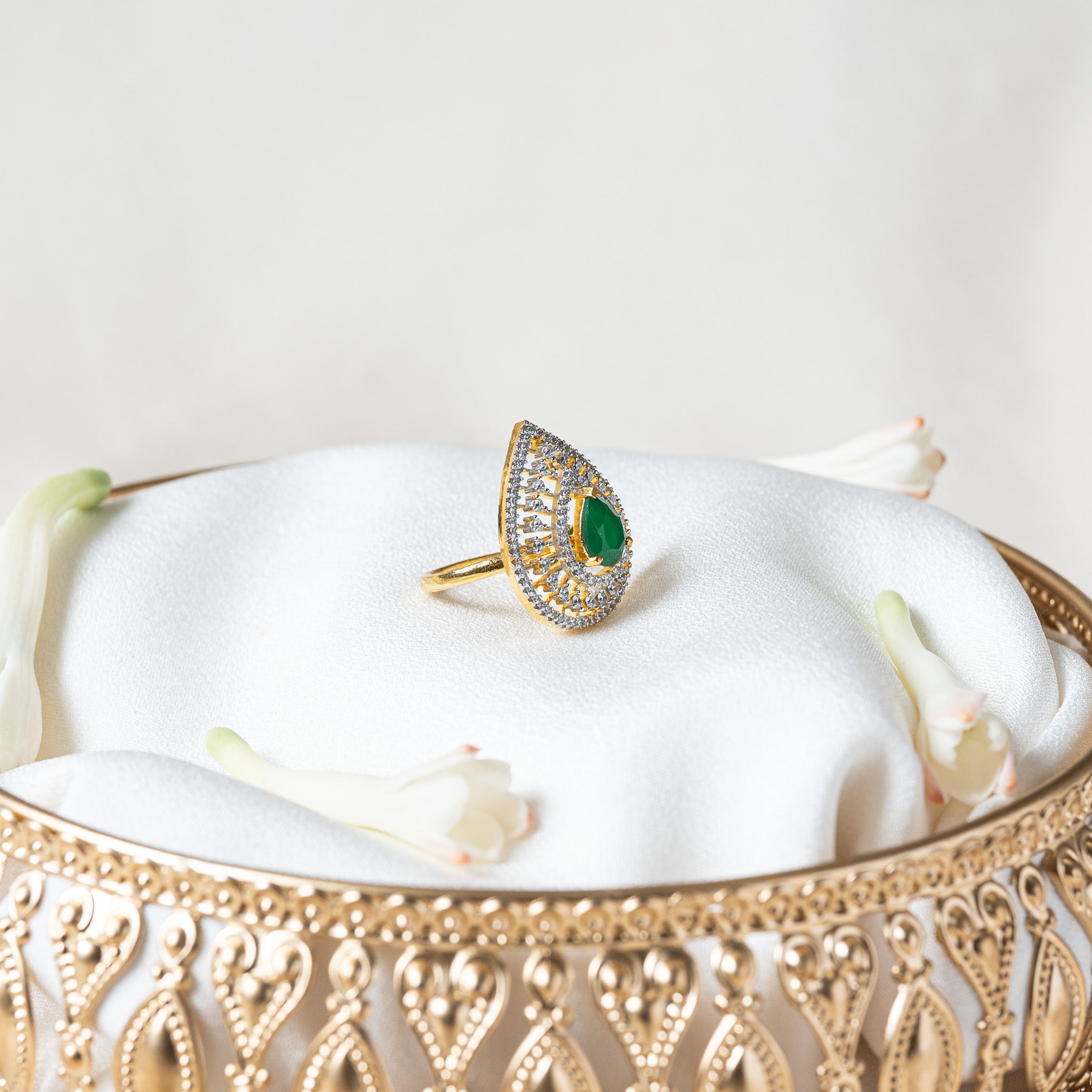 Side view of the green teardrop ring showing the prong set centre stone standing above the rows of CZ
