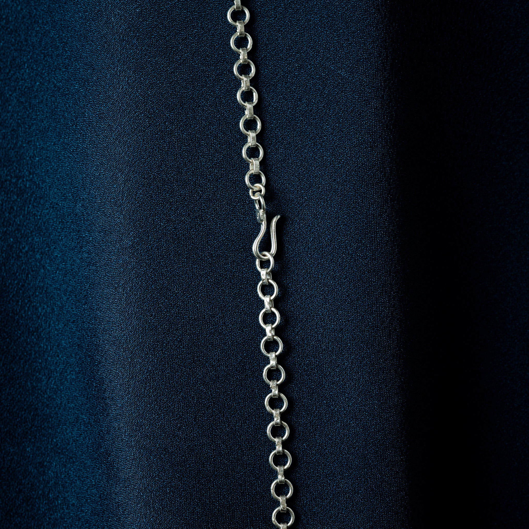 Mid-chain S-hook on a silver round link back chain, close crop