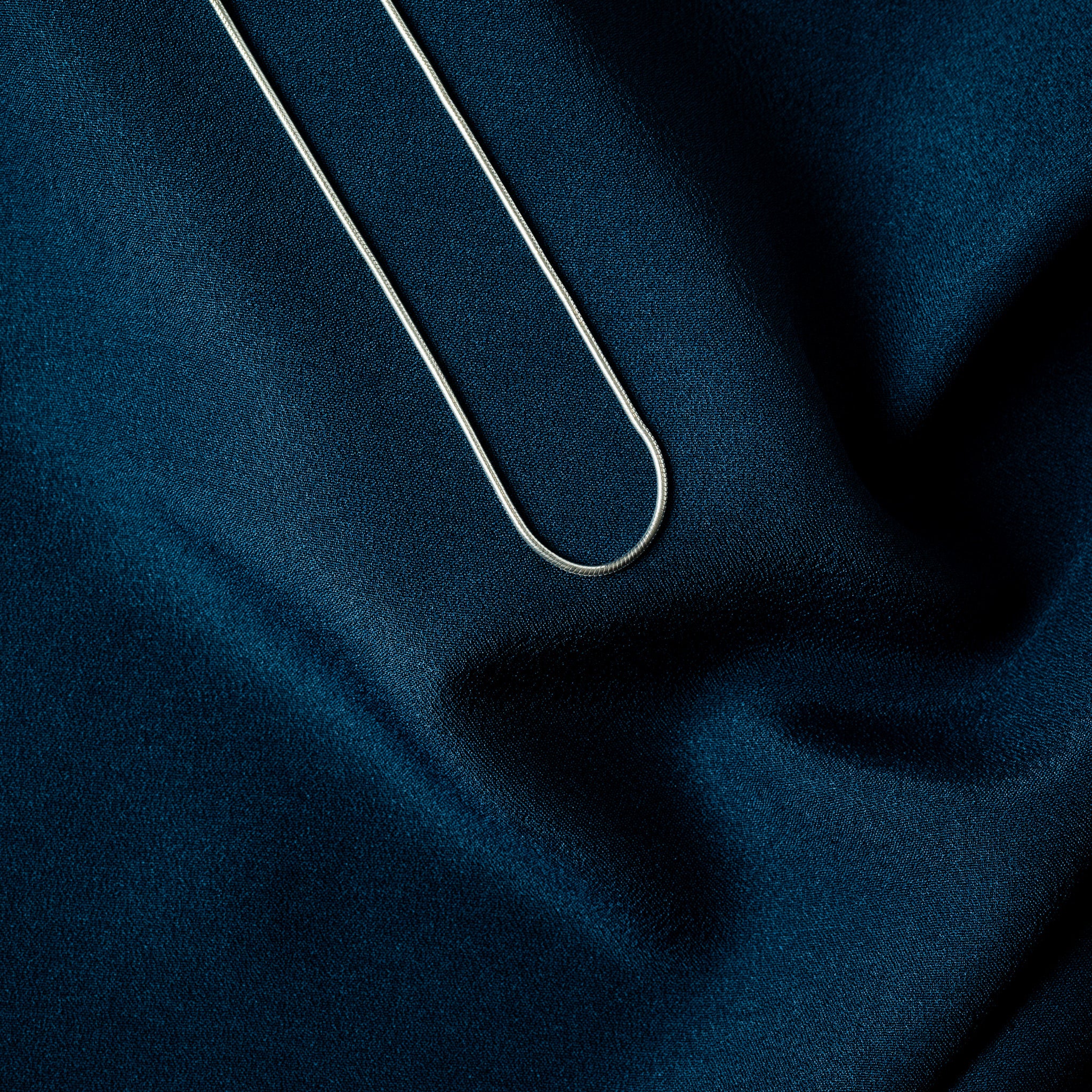 Crimped end cap, jump ring and lobster clasp on a silver snake chain, macro